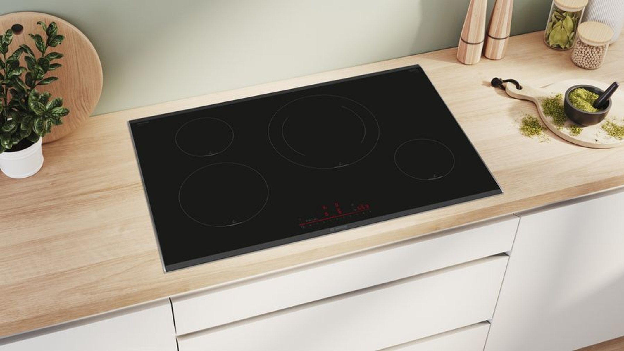 Zwarte inductiekookplaat op licht houten oppervlak in keuken met witte kasten.