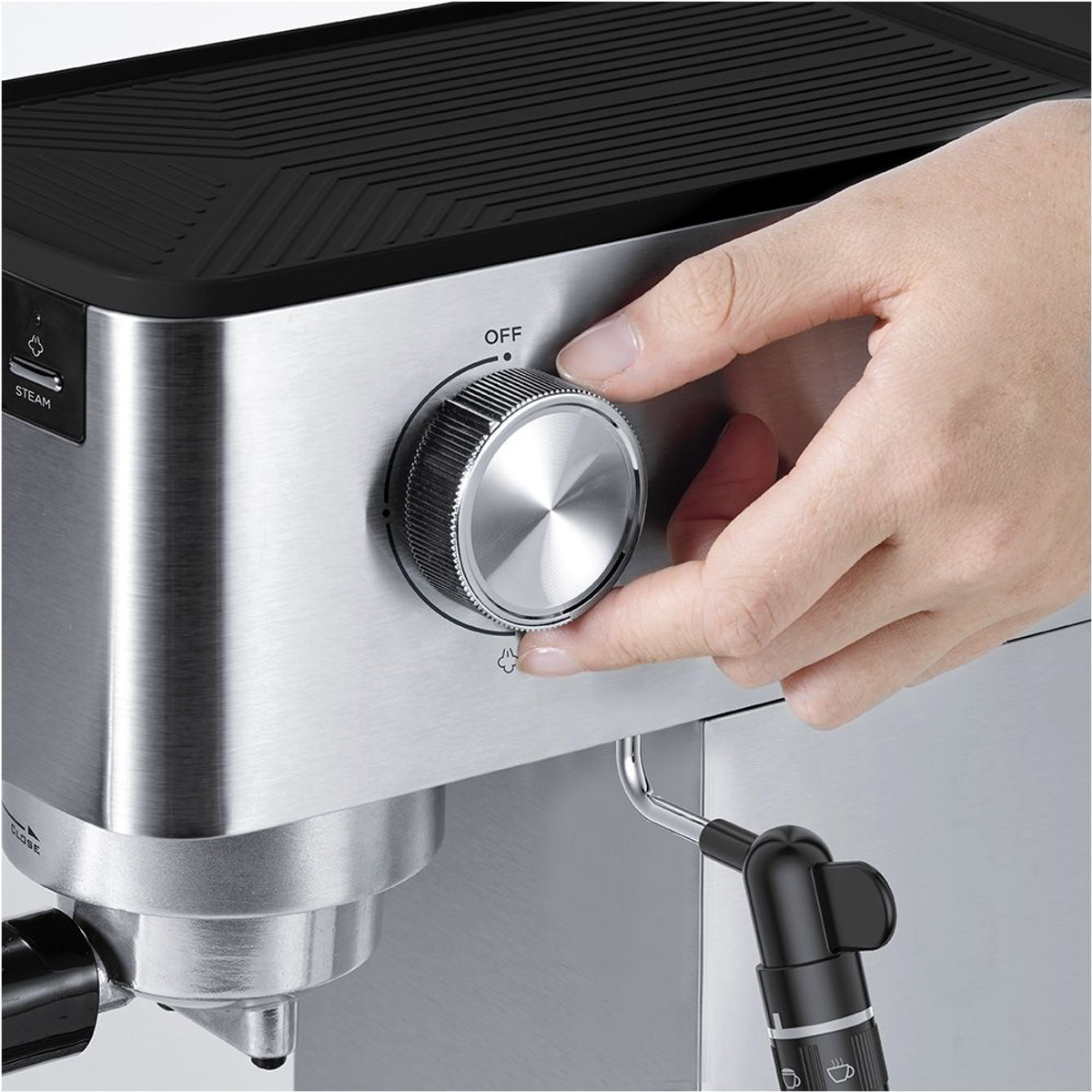 Una mano ruota una manopola su una macchina per caffè espresso argentata sulla posizione 'OFF'. Macchina in acciaio inossidabile.