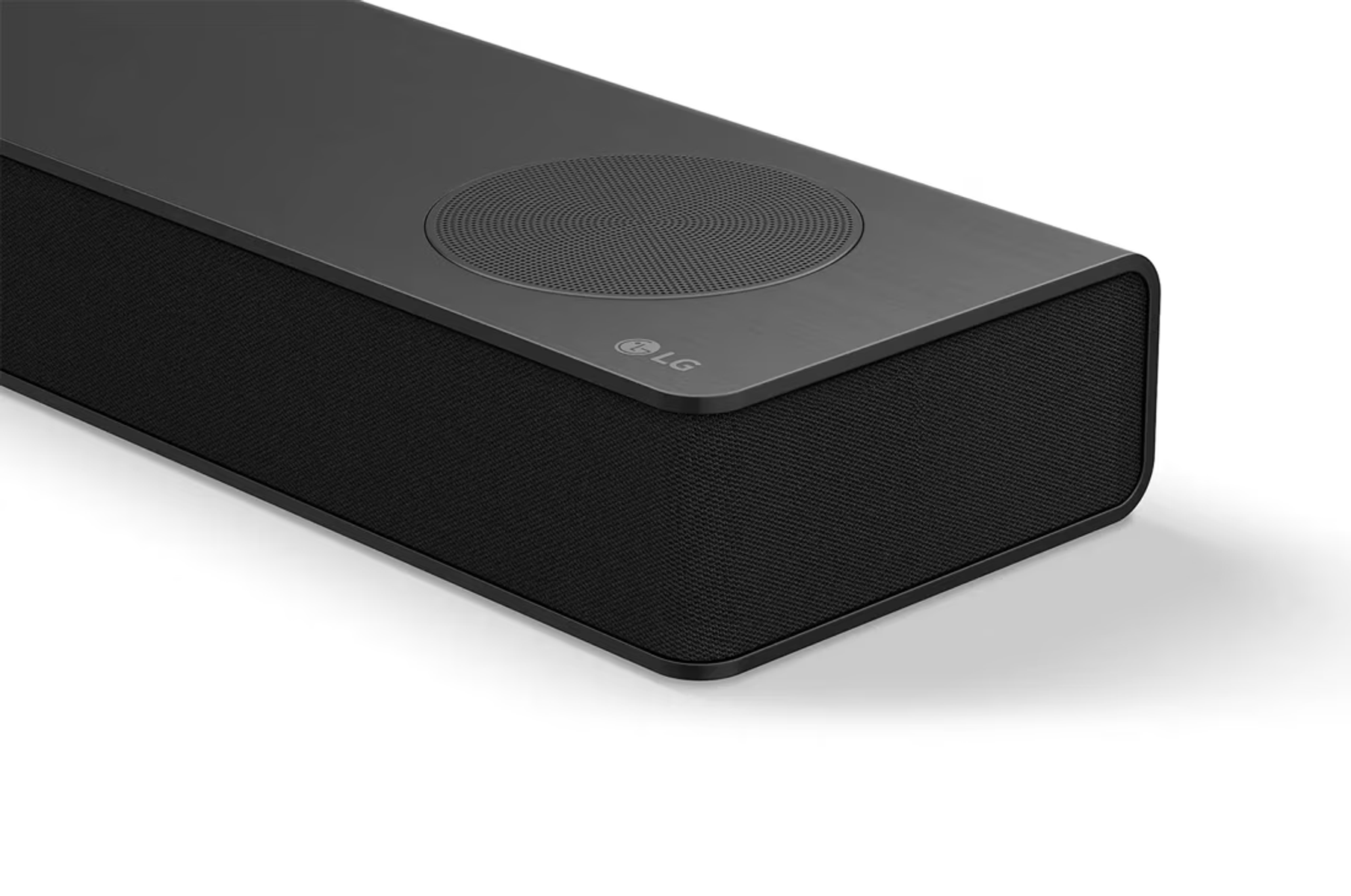 Barra de sonido LG. Negra, rectangular, con rejilla de altavoz y logo LG. La parte superior tiene un altavoz redondo.