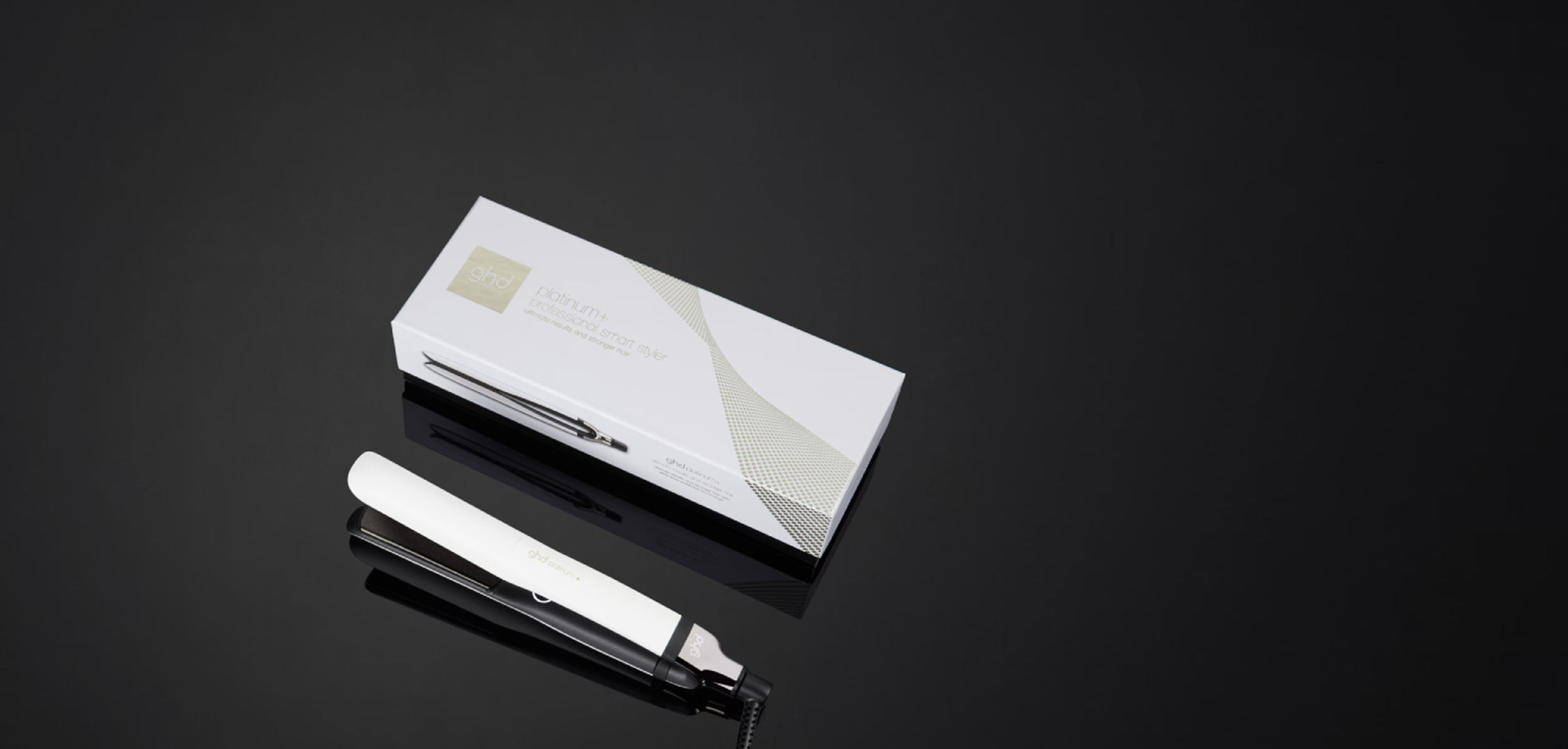 Weißer Haarglätter und Box auf schwarzer, reflektierender Oberfläche. GHD-Logo.
