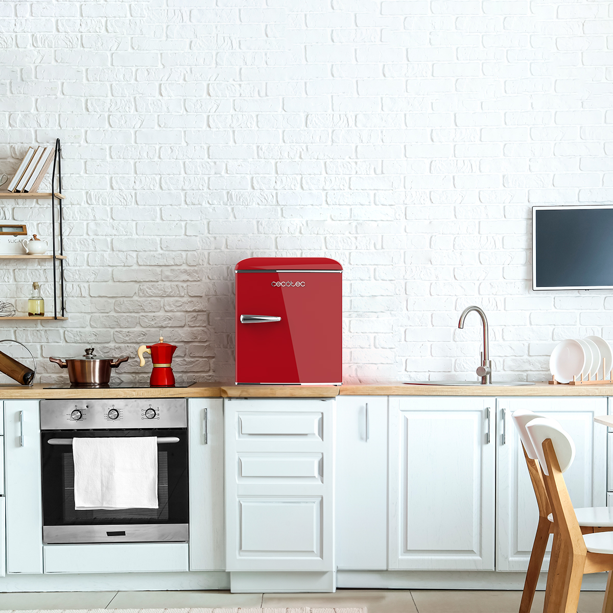 Mini-frigorifero rosso in cucina con mobili bianchi, forno e parete in mattoni.