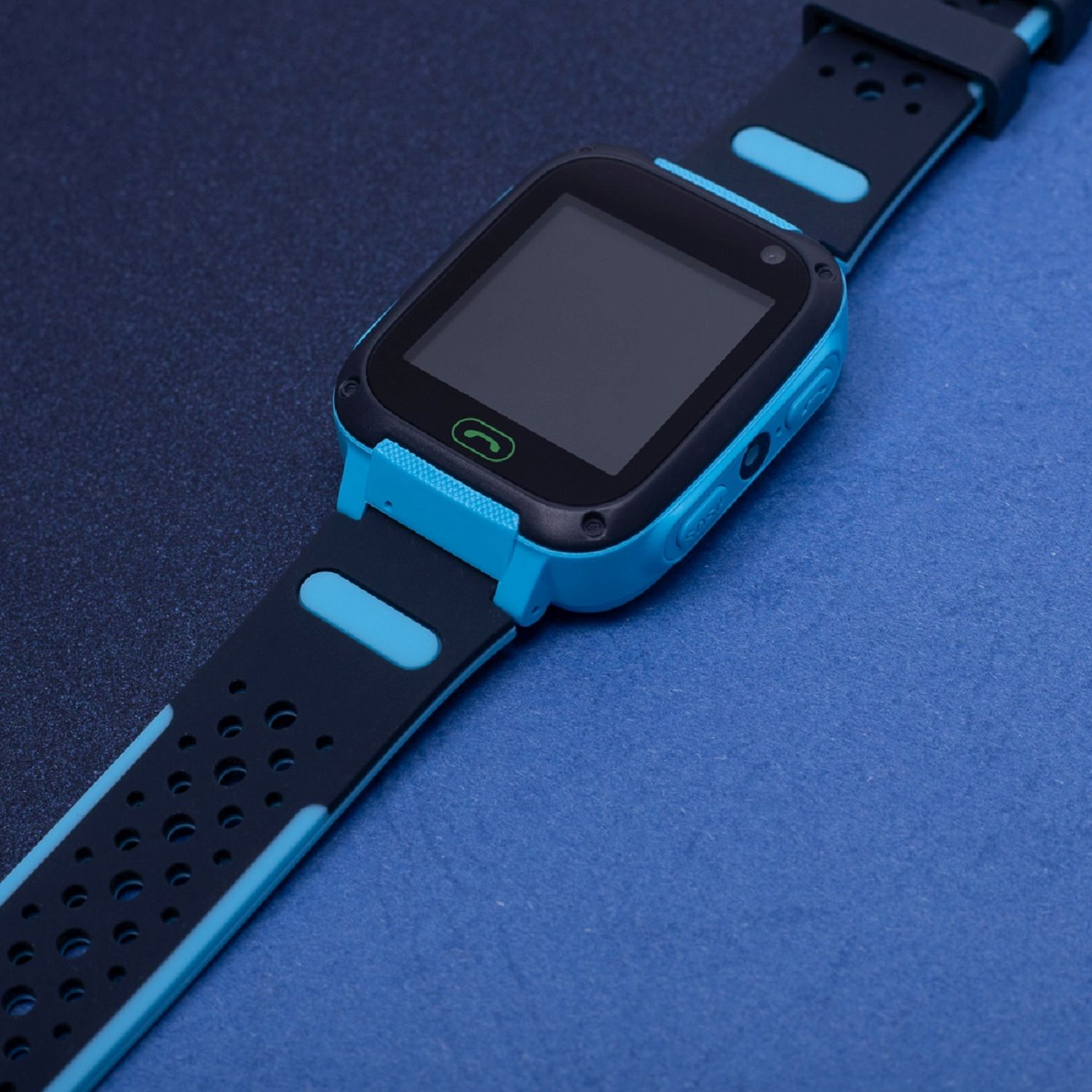 Blaue und schwarze Smartwatch auf einer blauen Oberfläche. Sie hat einen schwarzen Bildschirm und ein schwarzes Armband.