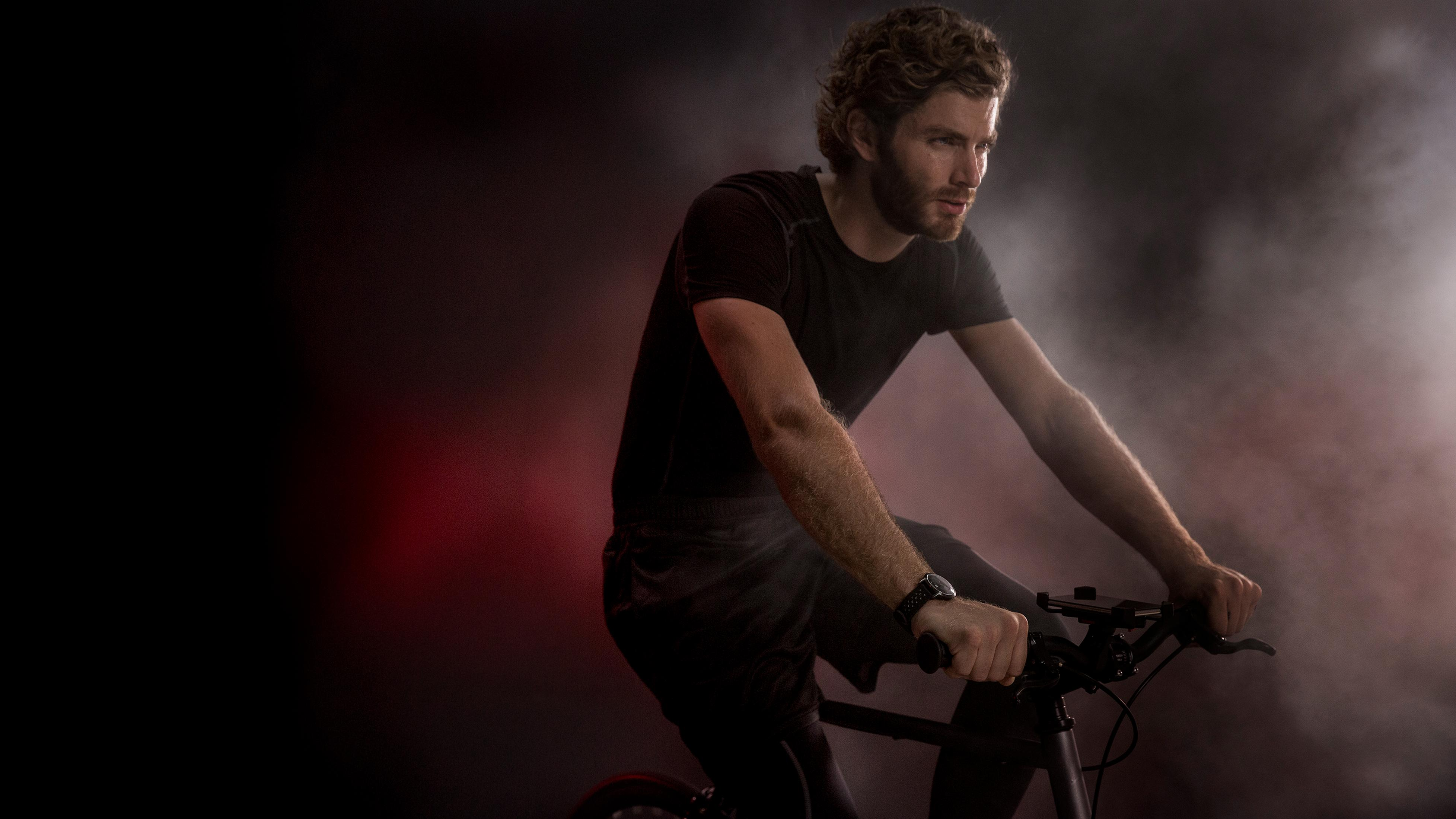Ein Mann fährt Fahrrad in einer rot getönten, rauchigen Umgebung, nach rechts blickend, entschlossen.