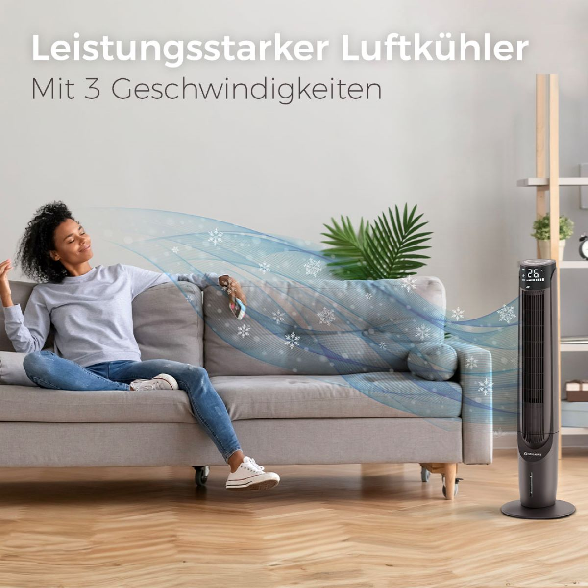 Eine Frau sitzt auf einem grauen Sofa und genießt den Luftstrom eines schwarzen Stand-Luftkühlers.