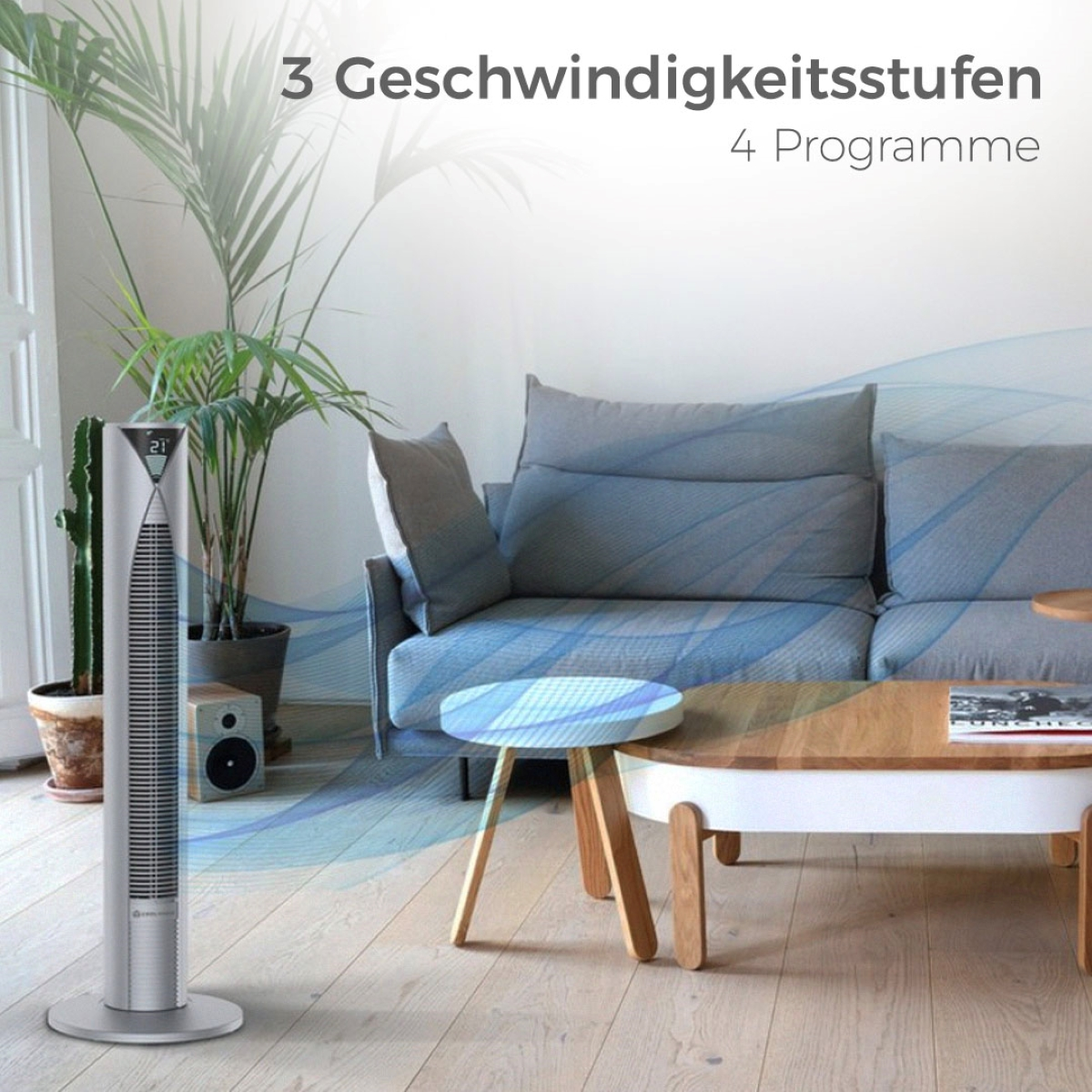 Silberner Ventilator mit Digitalanzeige und Text. Wohnzimmer mit Sofa und Pflanzen.