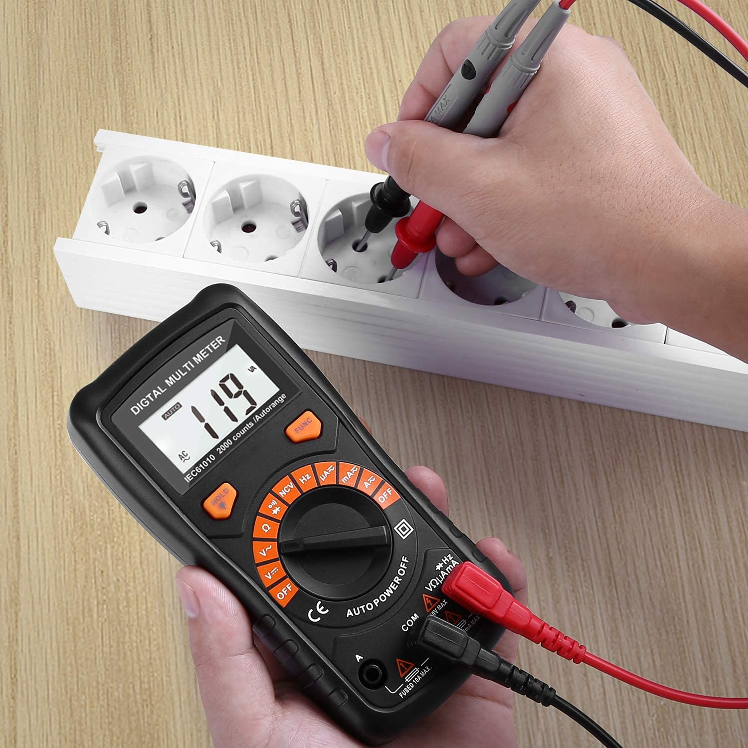 Digitales Multimeter misst Steckdose. Der Bildschirm zeigt einen Wert. Schwarze und rote Sonden.