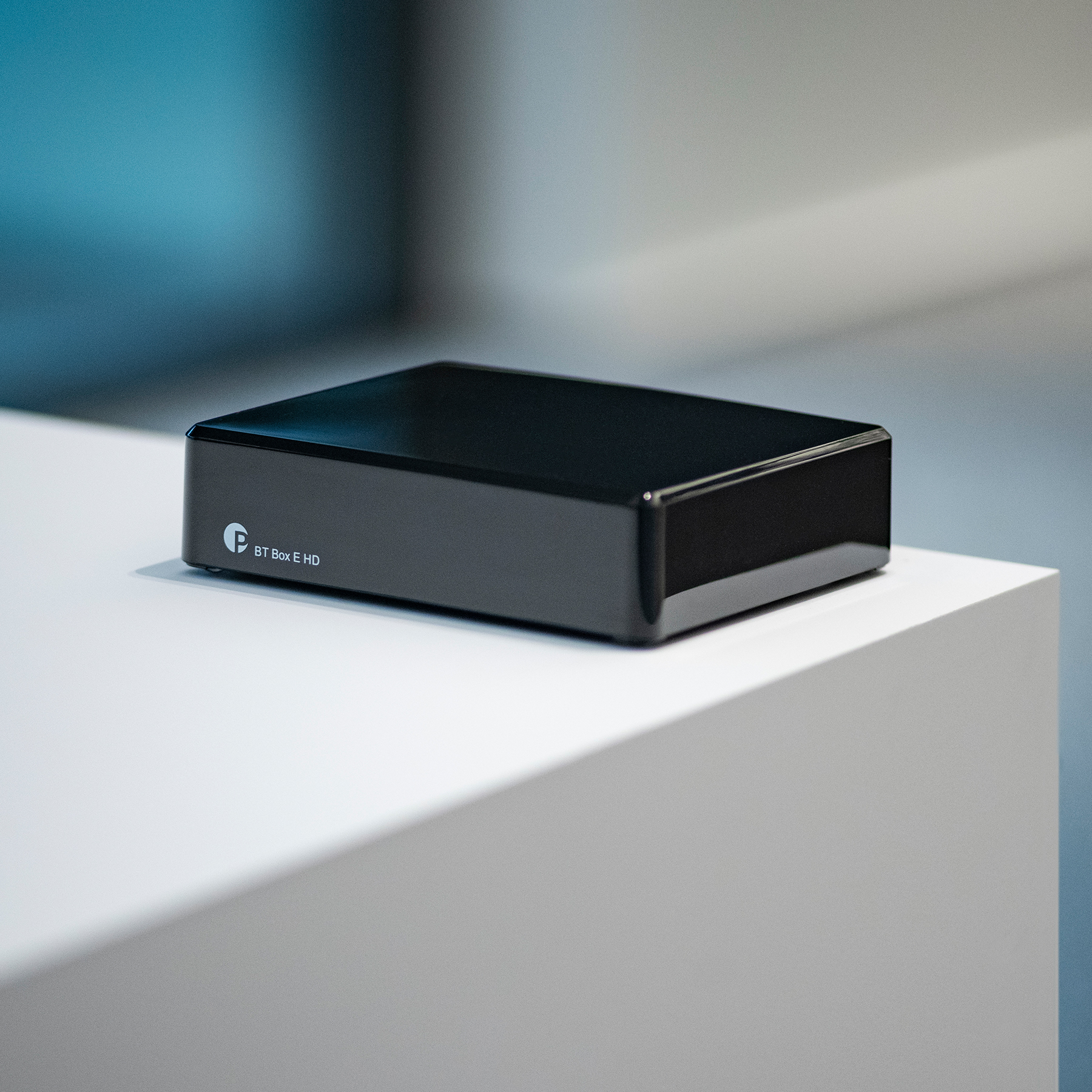 Une petite boîte noire sur une surface blanche, avec un logo. Le fond est flou.