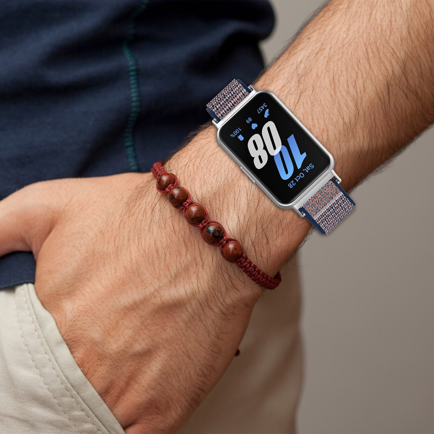 Ein Handgelenk mit Uhr und Perlenarmband. Die Uhr zeigt eine Zeit an.