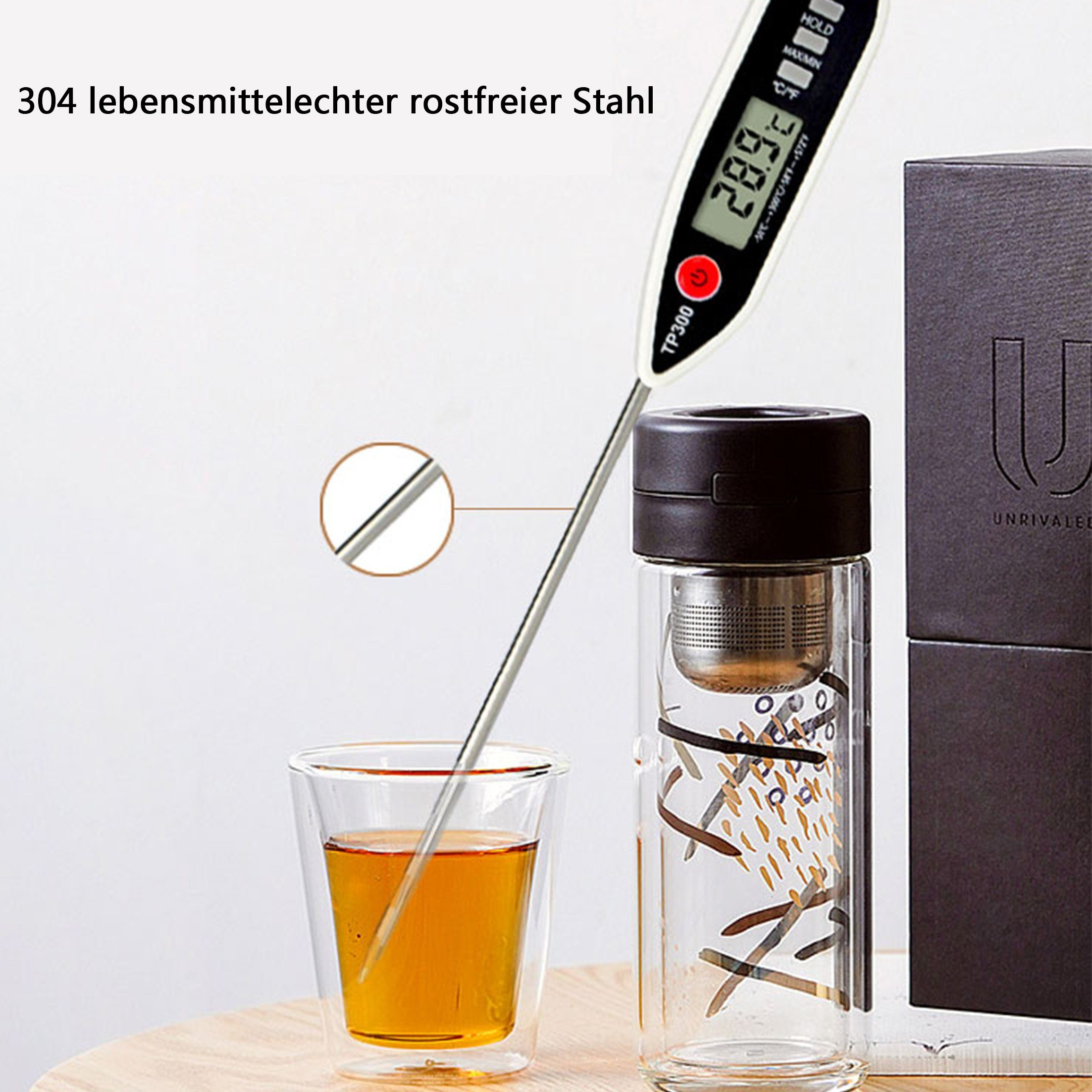 Ein Thermometer misst Flüssigkeit in einem Glas. Tee ist im Glas und eine Teekanne befindet sich rechts.