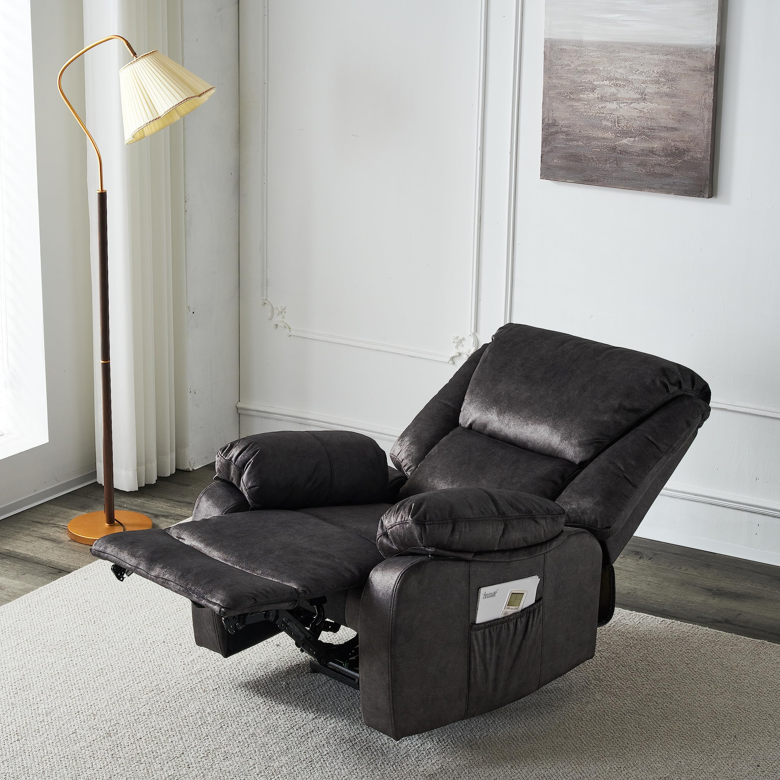 Sillón reclinable gris oscuro con reposapiés extendido, en una habitación con lámpara y pintura.