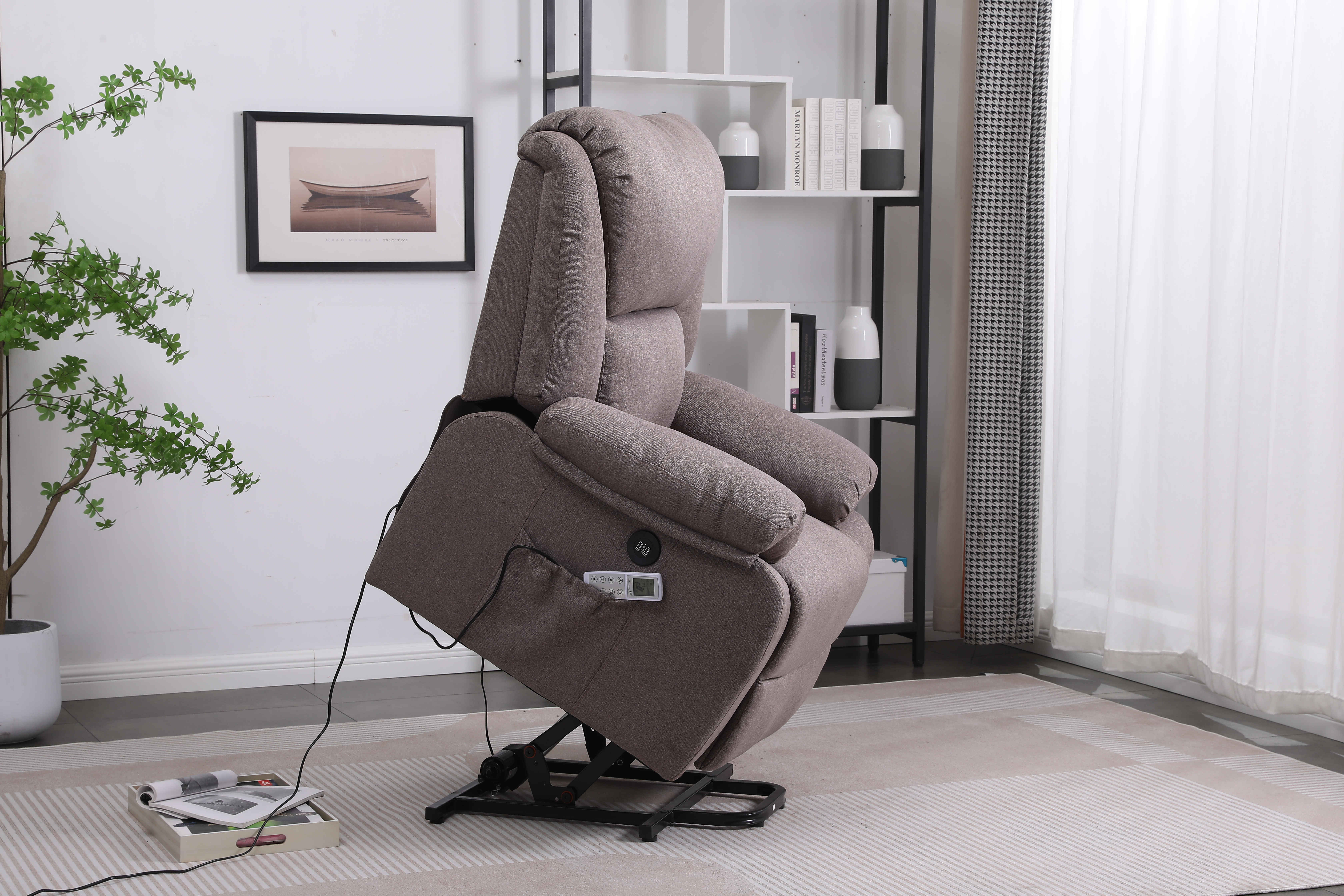 Un sillón reclinable gris en una habitación, con una mesa auxiliar y una planta. La silla está reclinada.