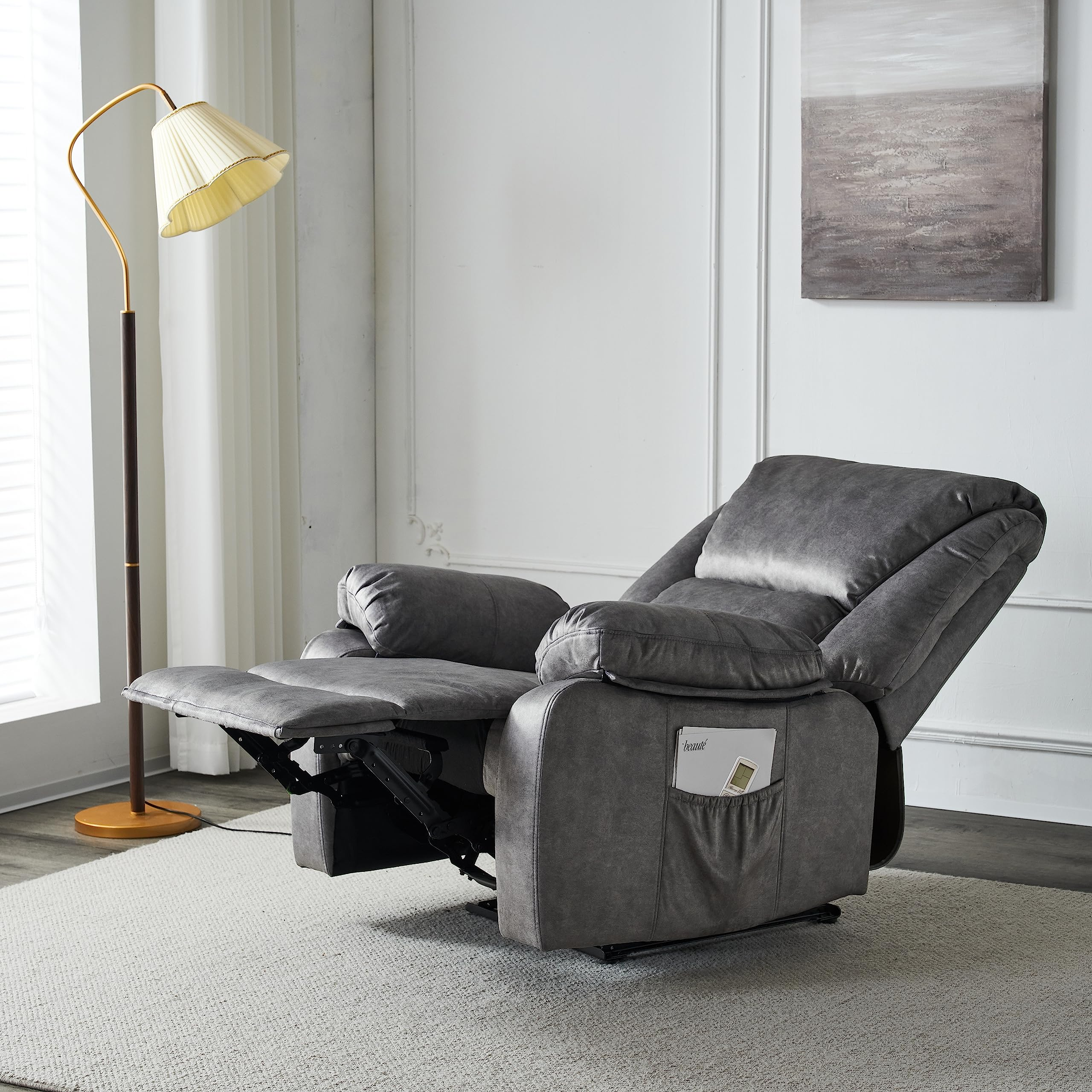 Sillón reclinable gris en una sala de estar, con lámpara de pie y obras de arte.