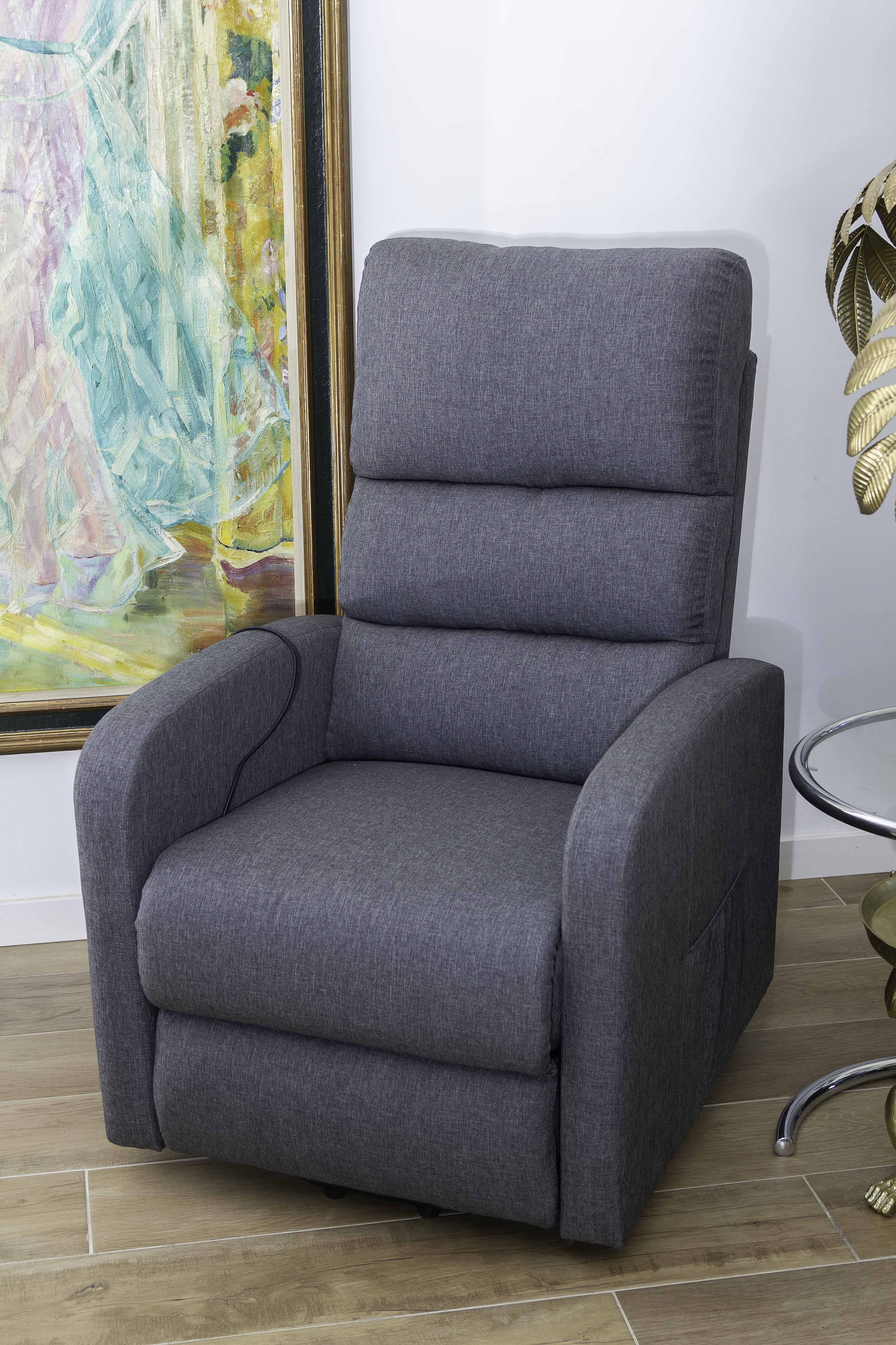 Sillón reclinable gris en una habitación con una pintura y una mesa auxiliar de cristal.