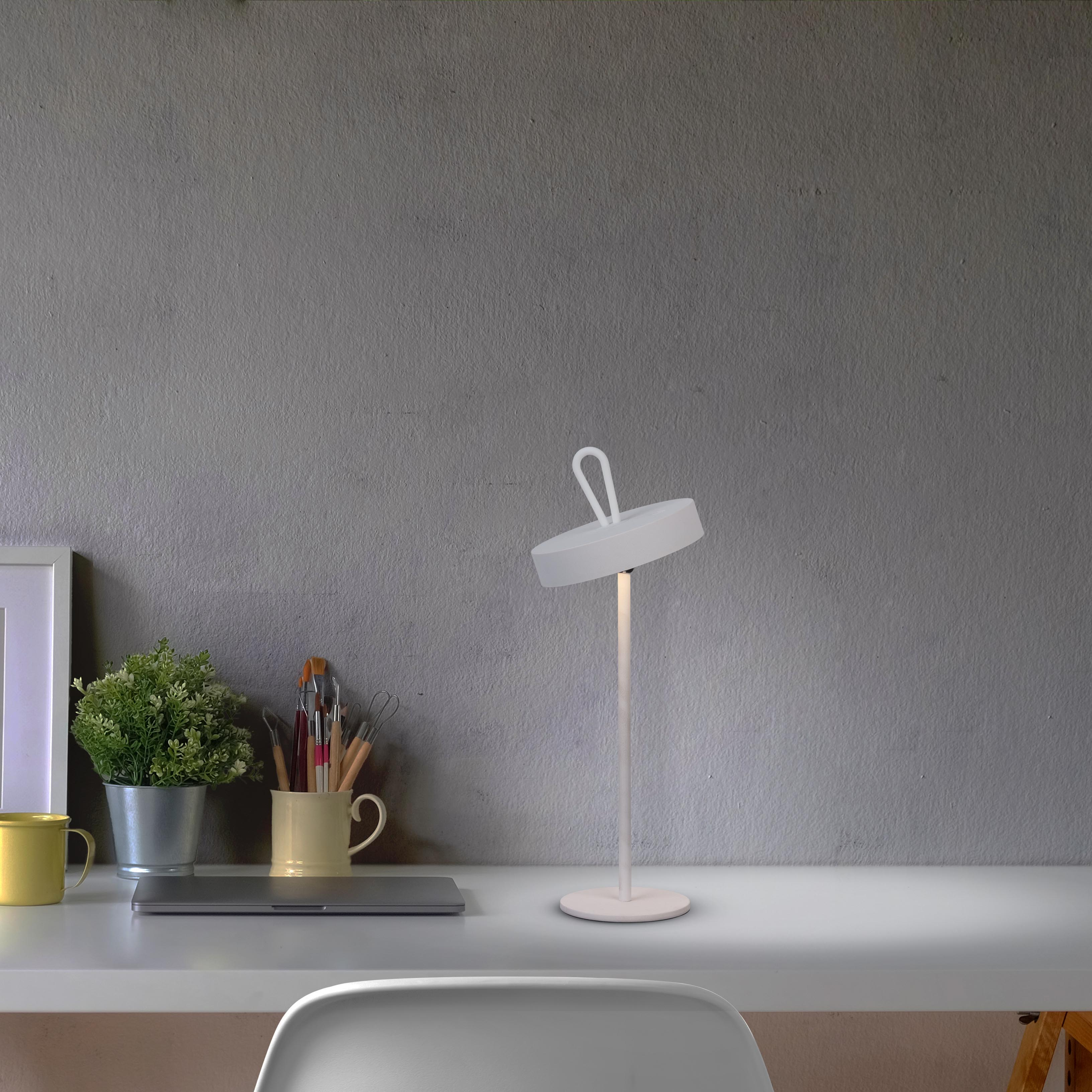 Weiße Lampe auf einem weißen Tisch mit verschiedenen Gegenständen. Grauer Wandhintergrund.