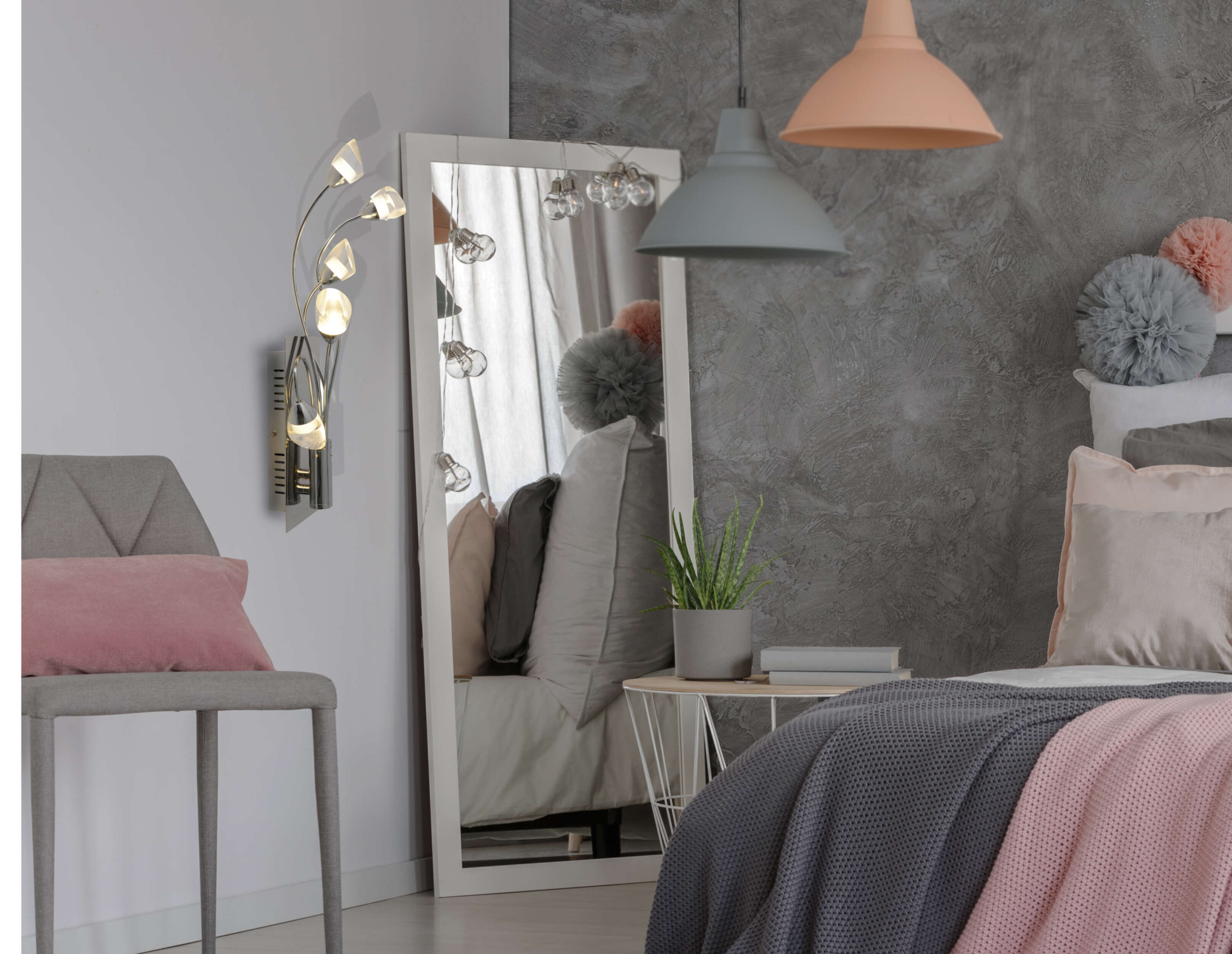 Schlafzimmer mit Spiegel, Bett, Tisch und Stuhl. Eine Wandlampe und eine Pendelleuchte sind sichtbar.
