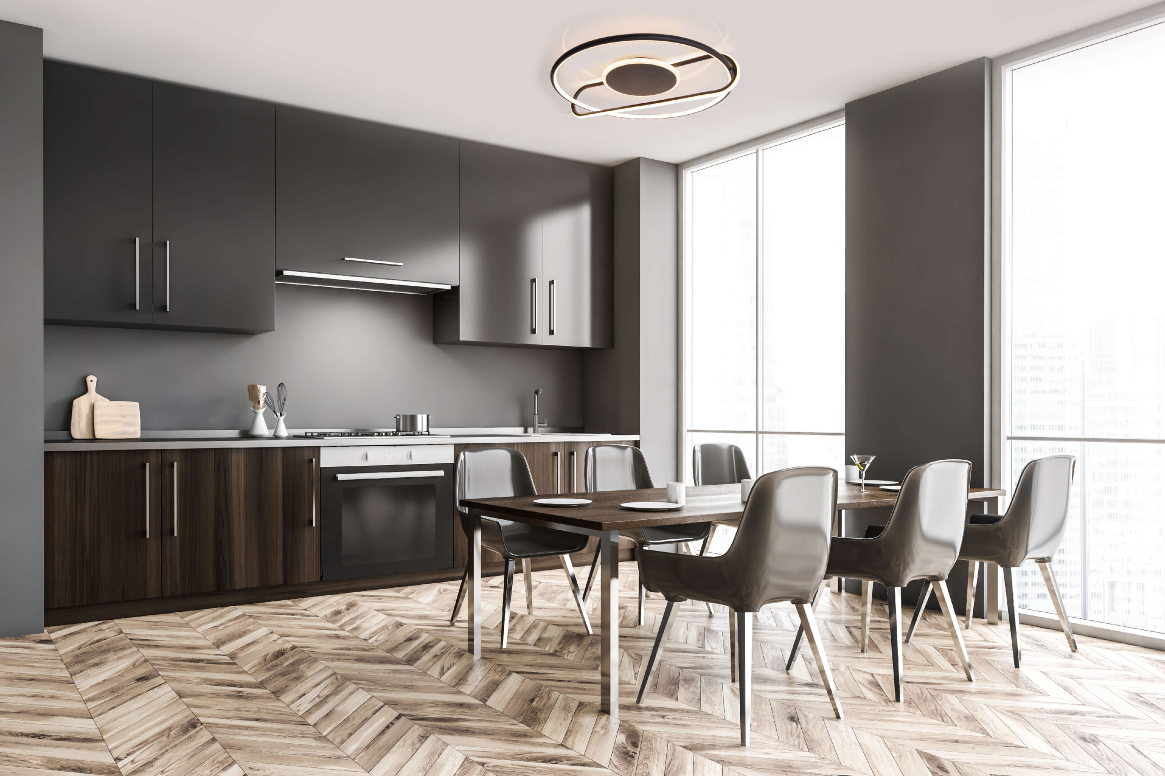 Moderne Küche mit dunklen Schränken, Holzboden, Tisch mit Stühlen und stilvoller Deckenleuchte.