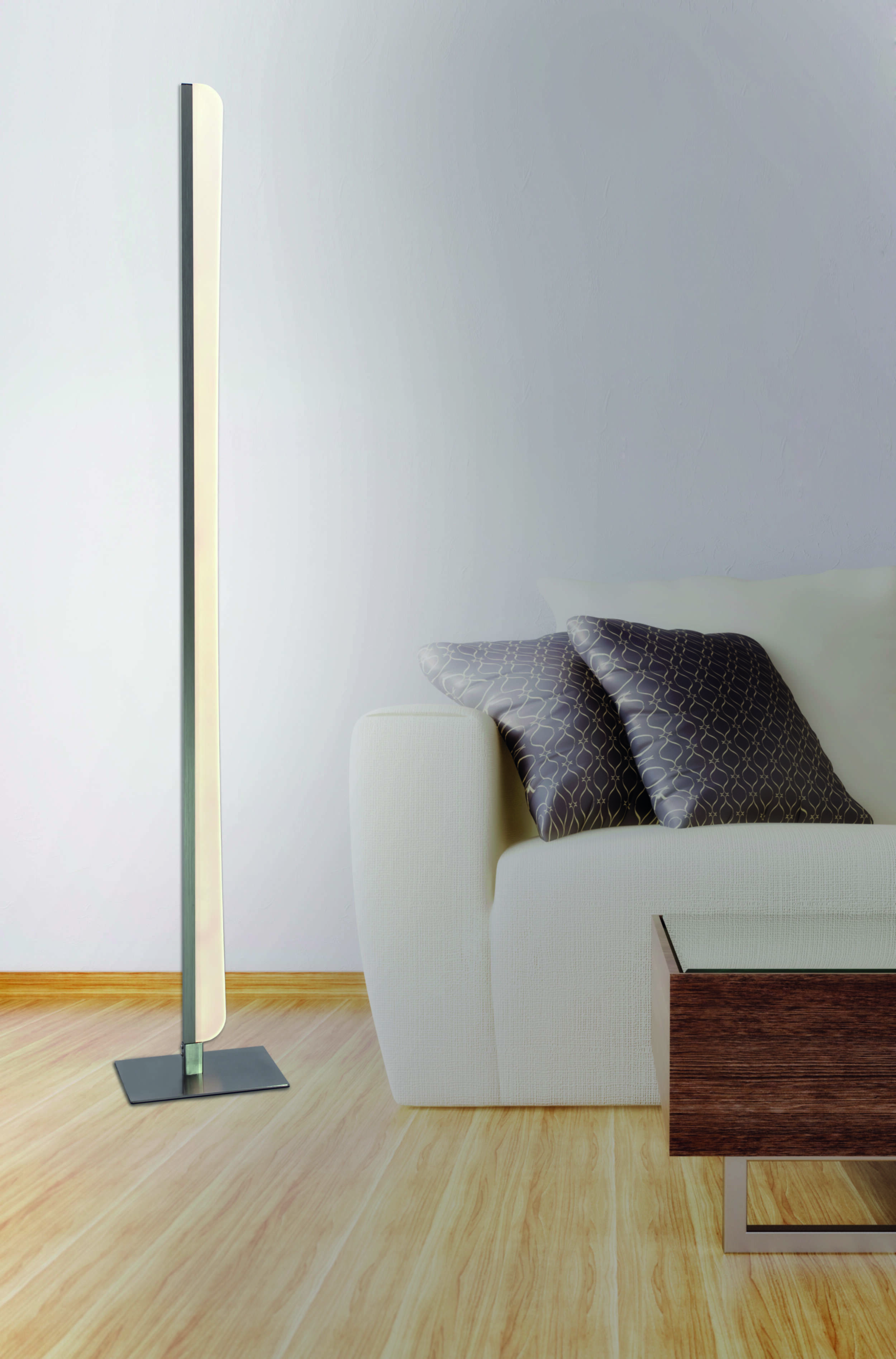 Eine hohe, schlanke Lampe mit modernem Design, neben einem weißen Sofa und einem Holztisch. Holzfußboden.
