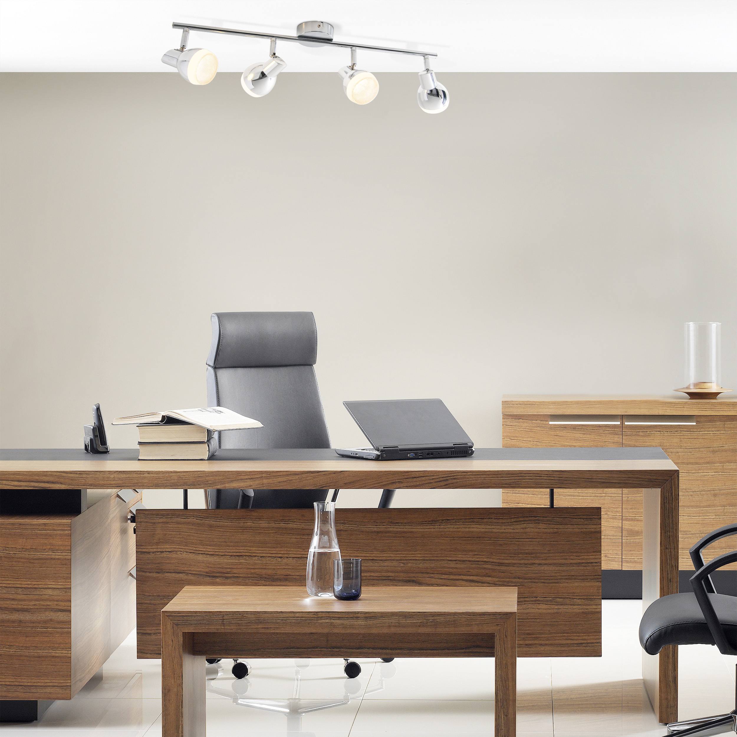 Ein Büro mit Schreibtisch, Stuhl und Deckenleuchte mit vier Strahlern.