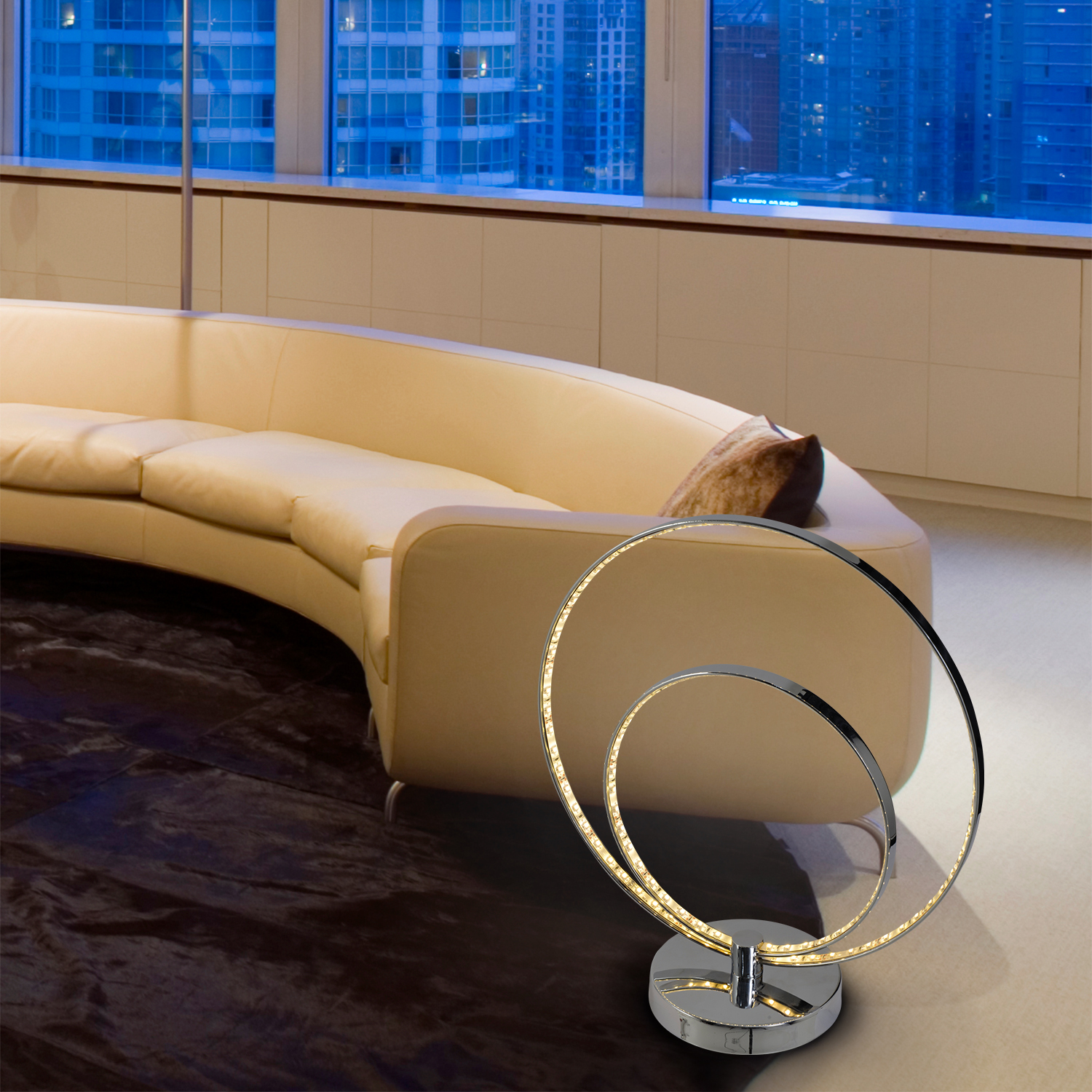 Eine moderne Lampe mit zwei beleuchteten Ringen auf Chrombasis, neben einem beigen Sofa.