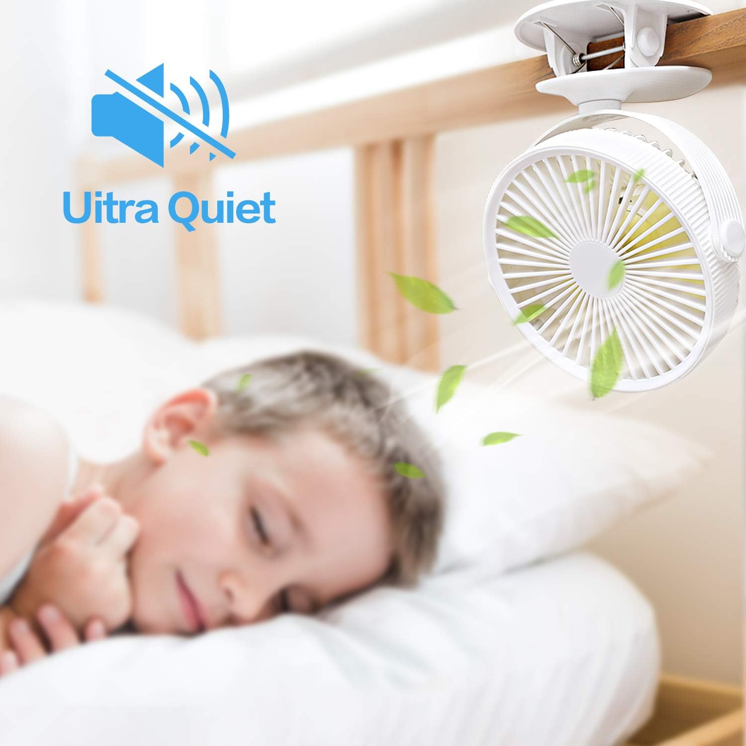 Ein kleiner weißer Ventilator ist an einem Bettrahmen befestigt und bläst Luft. Im Hintergrund schläft ein Kind.