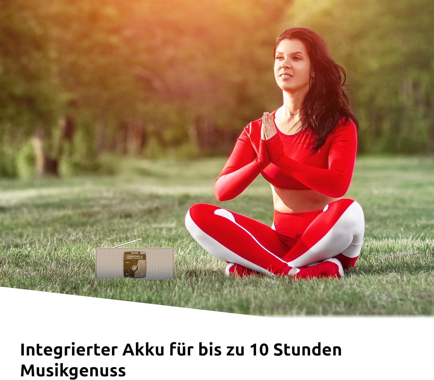 Kobieta w czerwonym stroju do jogi, ręce razem, w parku z głośnikiem.