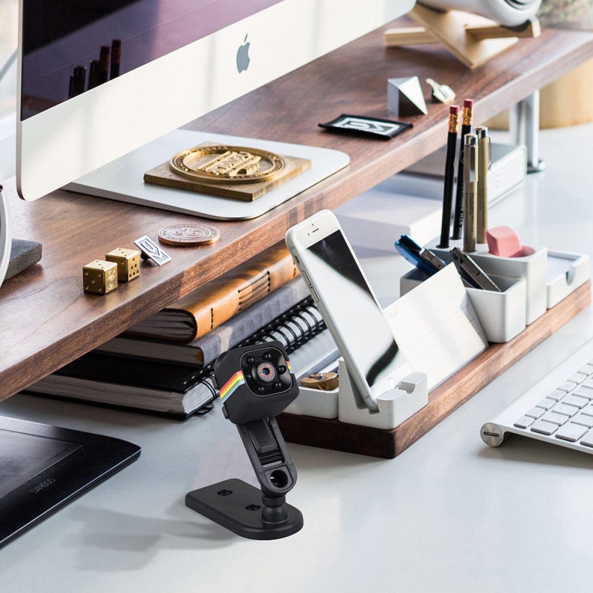 Schreibtisch-Setup mit Monitor, Webcam, Telefon und verschiedenen Schreibtischutensilien und Ordner.