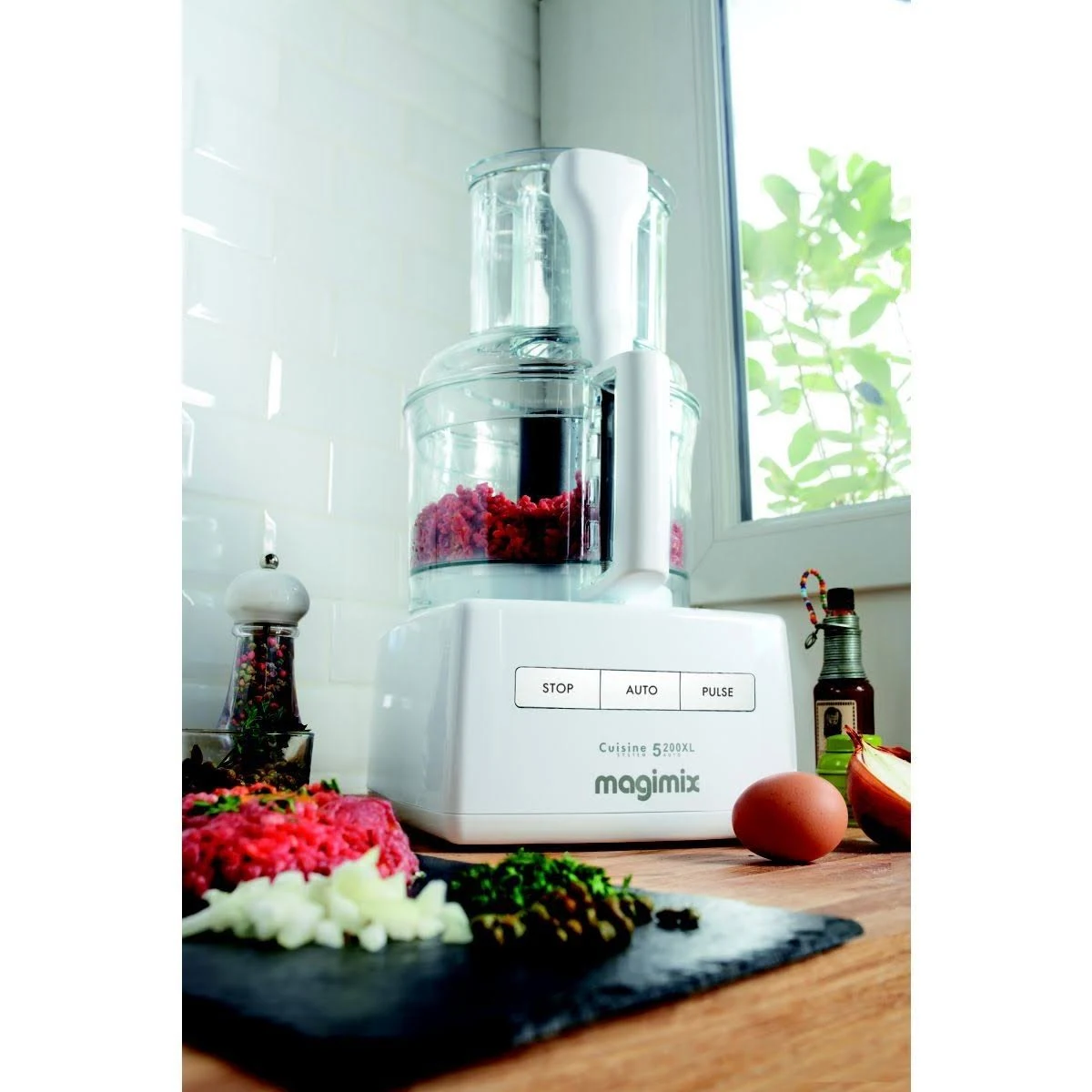 Un robot da cucina bianco con ingredienti, tra cui verdure tritate, su una superficie di legno.