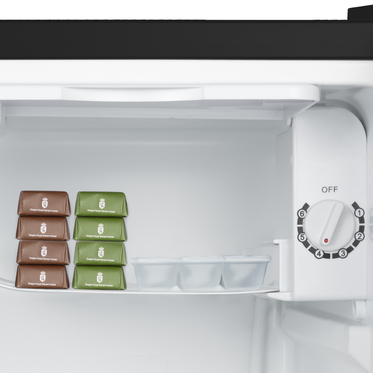 Interno di un mini frigo con cioccolatini, vaschette per il ghiaccio e pannello comandi.