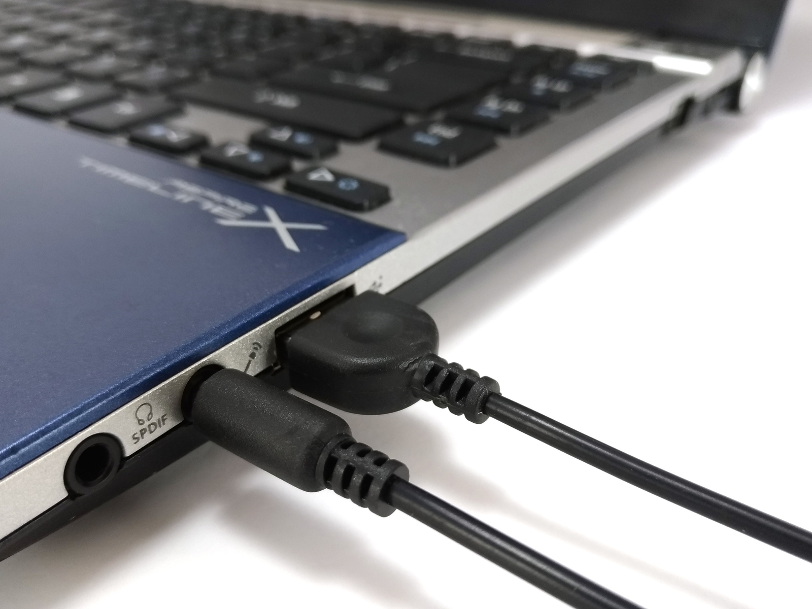 Primo piano di un laptop con cavi audio collegati, focus sulle porte e connettori.