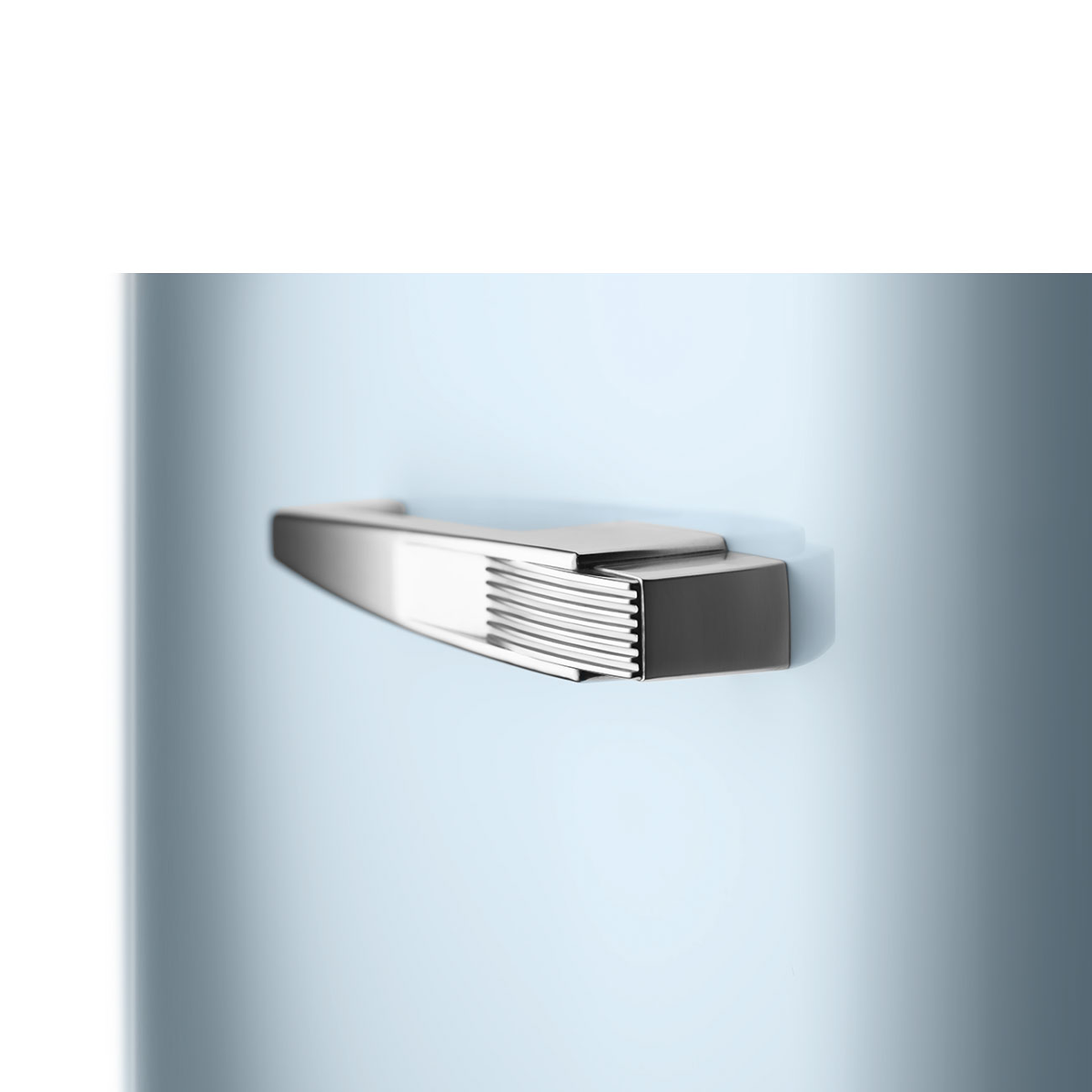 Primer plano de un tirador de puerta de refrigerador, plateado y rectangular sobre azul claro.