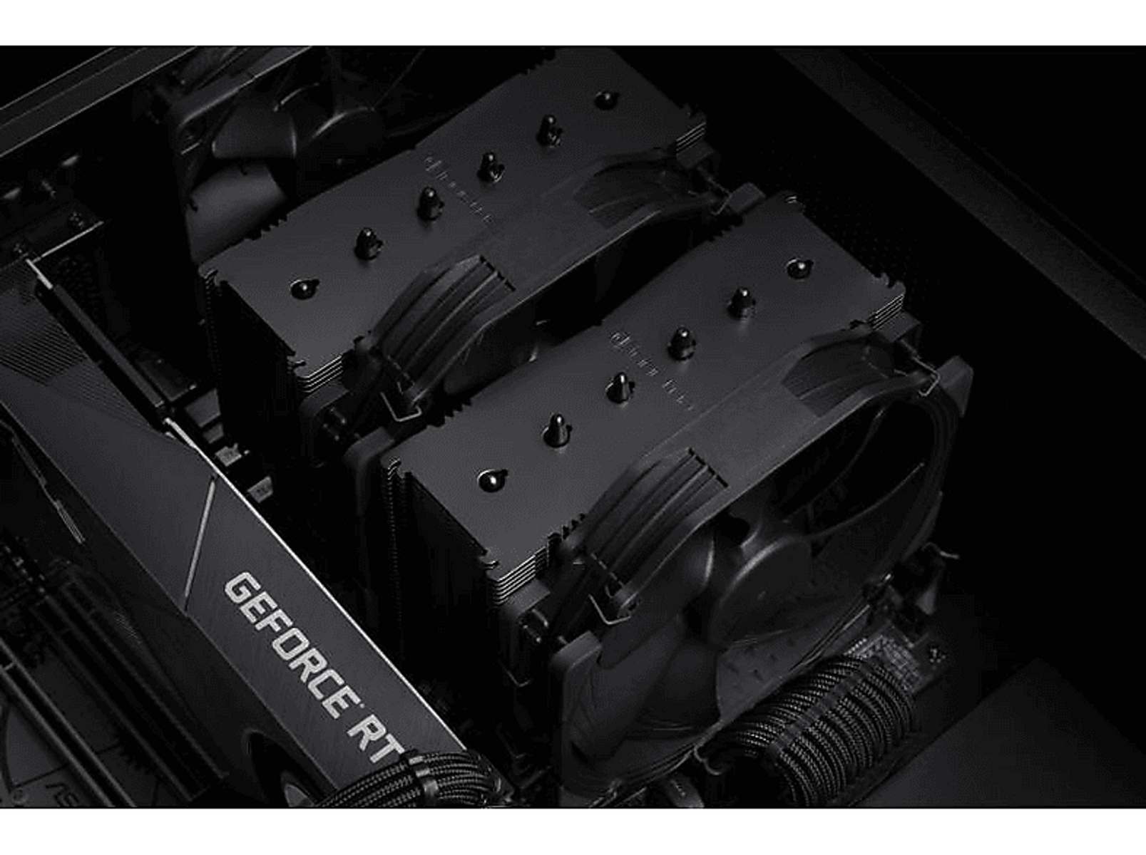 Komponenty komputera, czarne wentylatory i karta graficzna, w ciemnym otoczeniu.