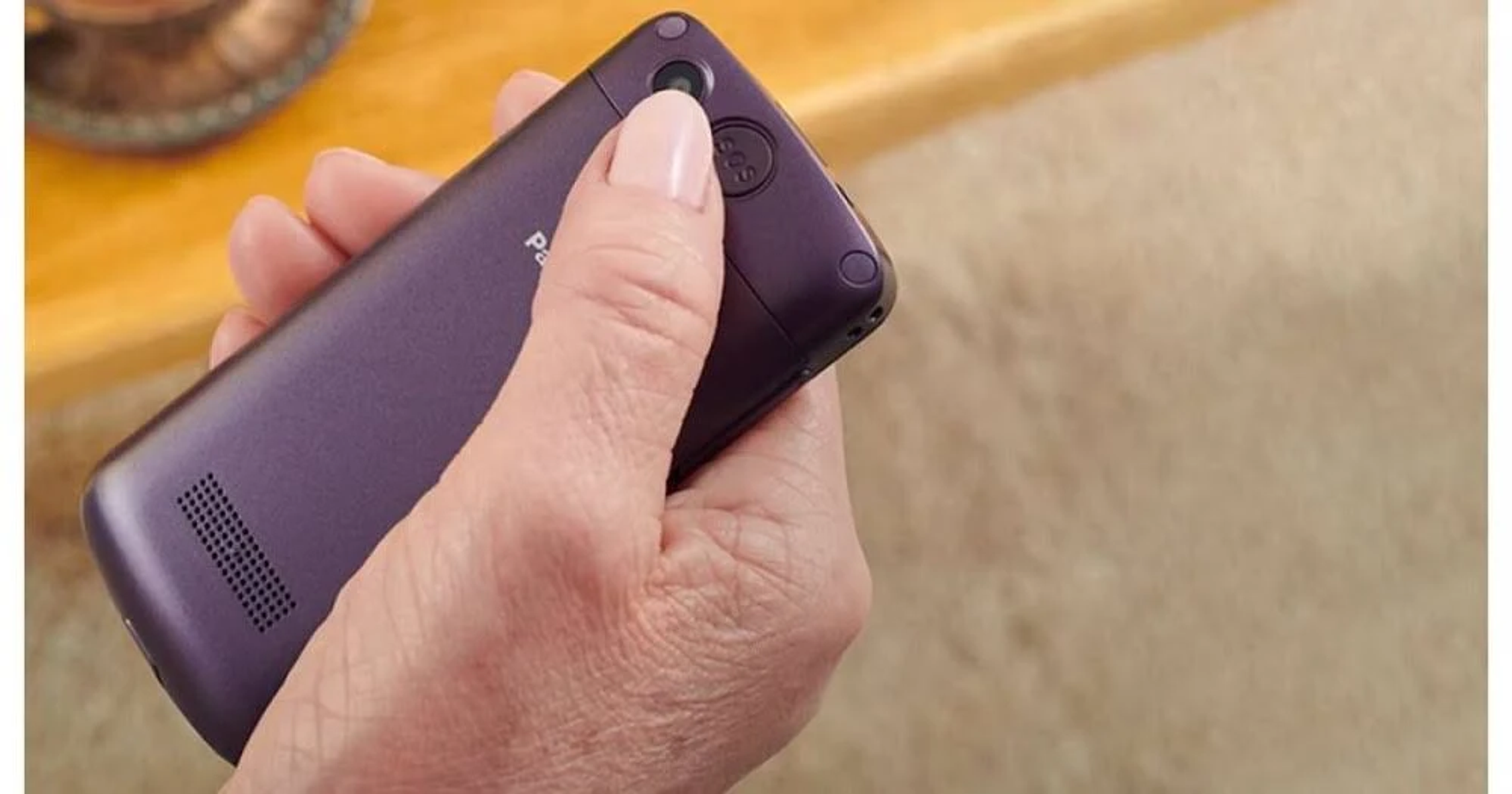 Die Hand einer Person, die ein lila Mobiltelefon mit Kamera hält.