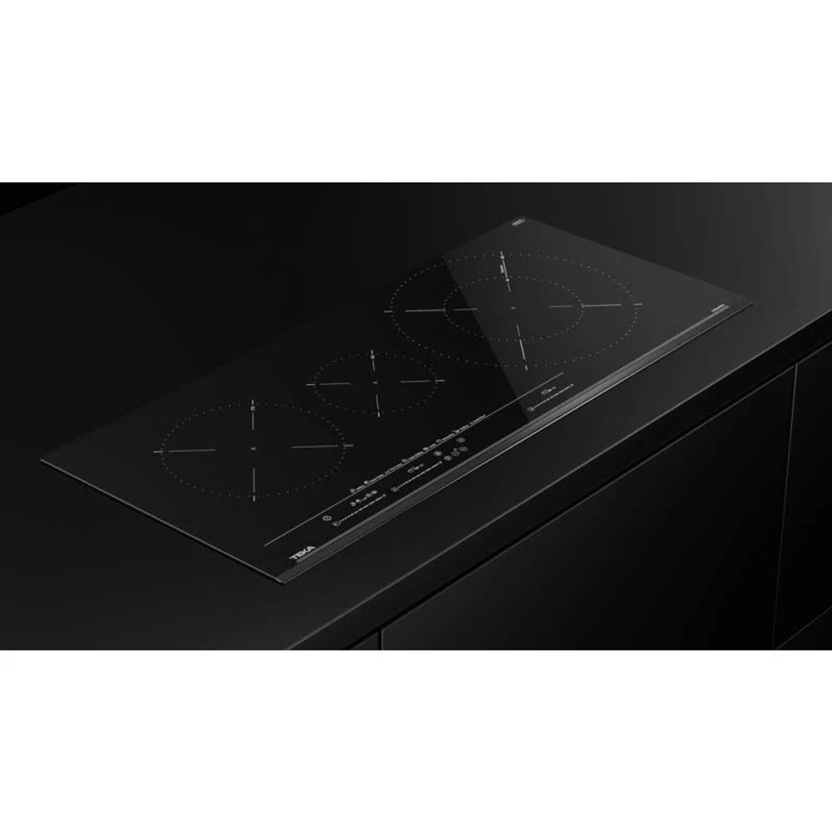 Czarna płyta indukcyjna z trzema strefami gotowania na czarnym blacie, widok z ukosa.