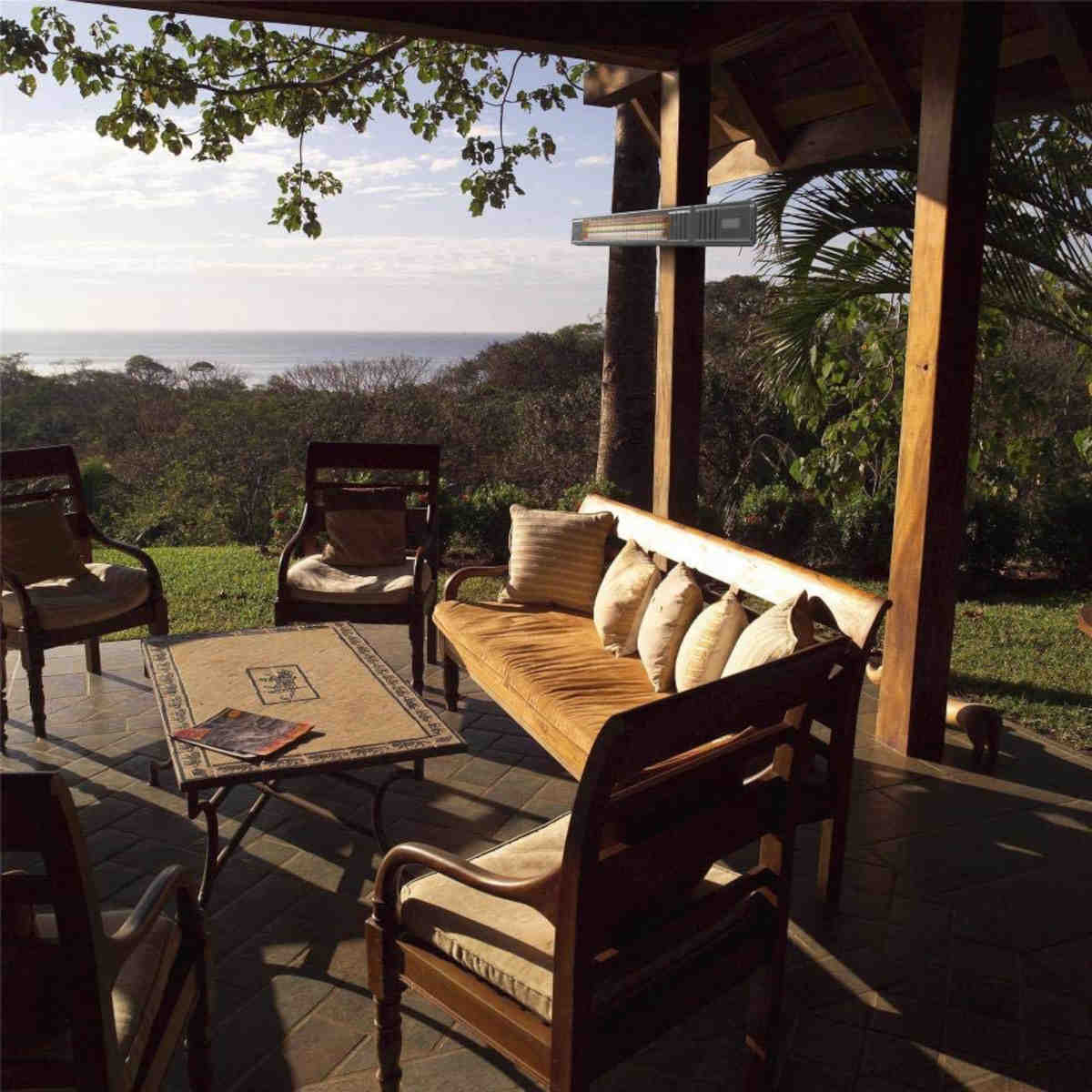 Außenbereich mit Tisch, Stühlen, einer Bank und Blick auf Bäume und das Meer.