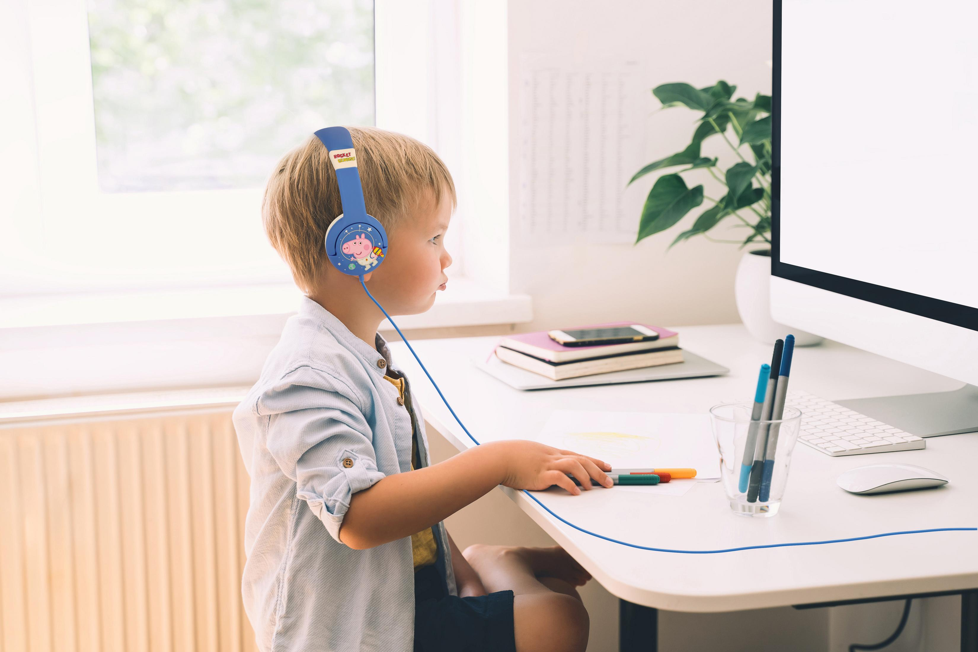Dziecko w niebieskich słuchawkach Peppa, rysuje przy biurku z komputerem.