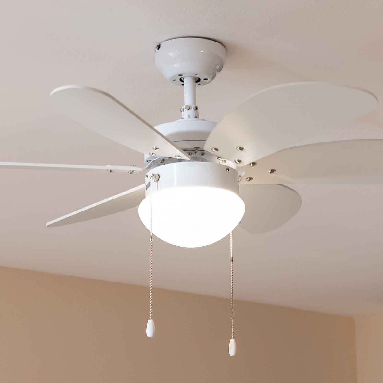 Ein grüner Retro-Ventilator steht auf einem Holzschrank mit Lampe und Pflanzen.