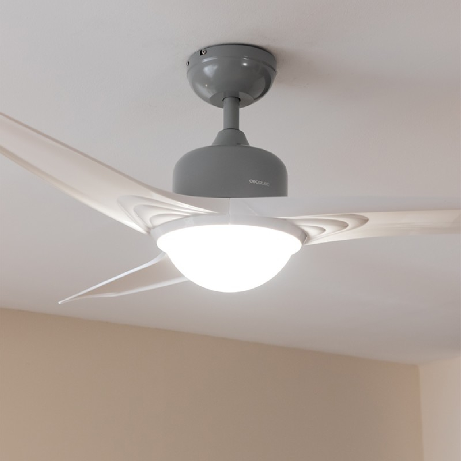 Ventilatore a soffitto con tre pale bianche e un alloggiamento motore grigio. Una luce è al centro.