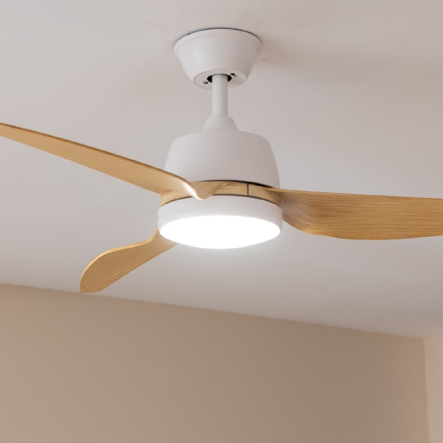 Ein weißer Deckenventilator mit drei Holzblättern und einer eingebauten Leuchte.