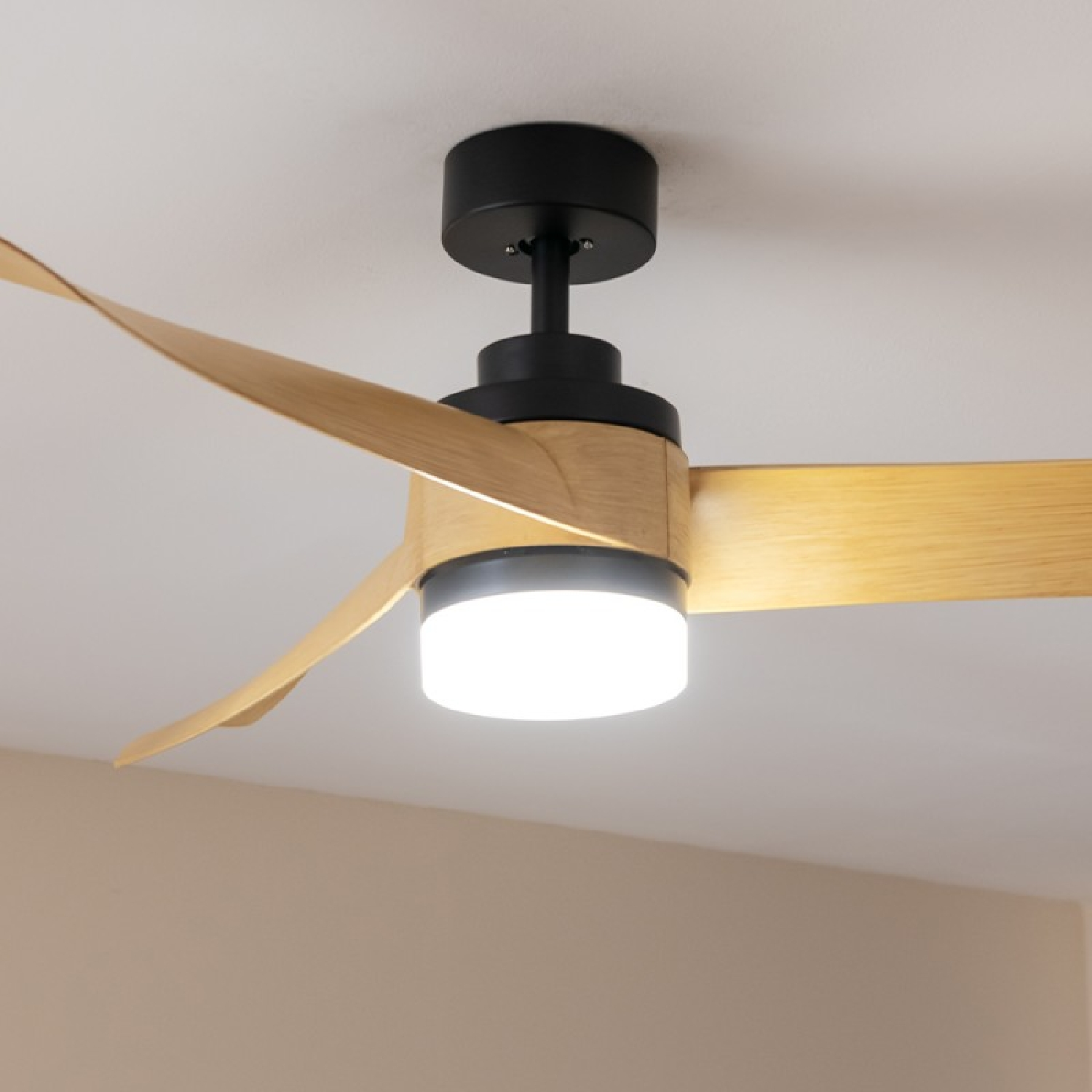 Ventilatore da soffitto con pale in legno e luce centrale. Montato su soffitto bianco.