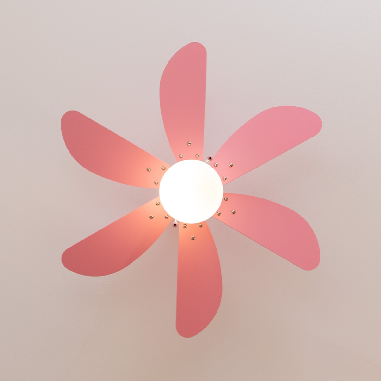 Ventilatore da soffitto con sei pale rosa, luce circolare bianca e sfondo del soffitto bianco.