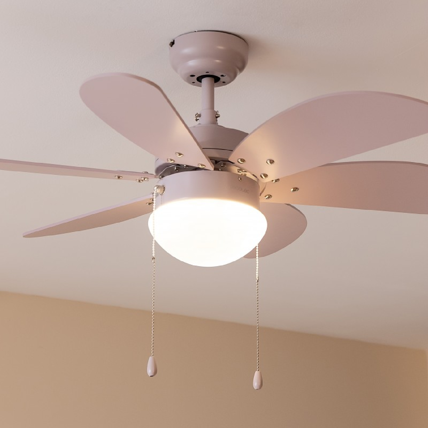Deckenventilator mit fünf hellrosa Flügeln, einer Leuchte und Zugketten.