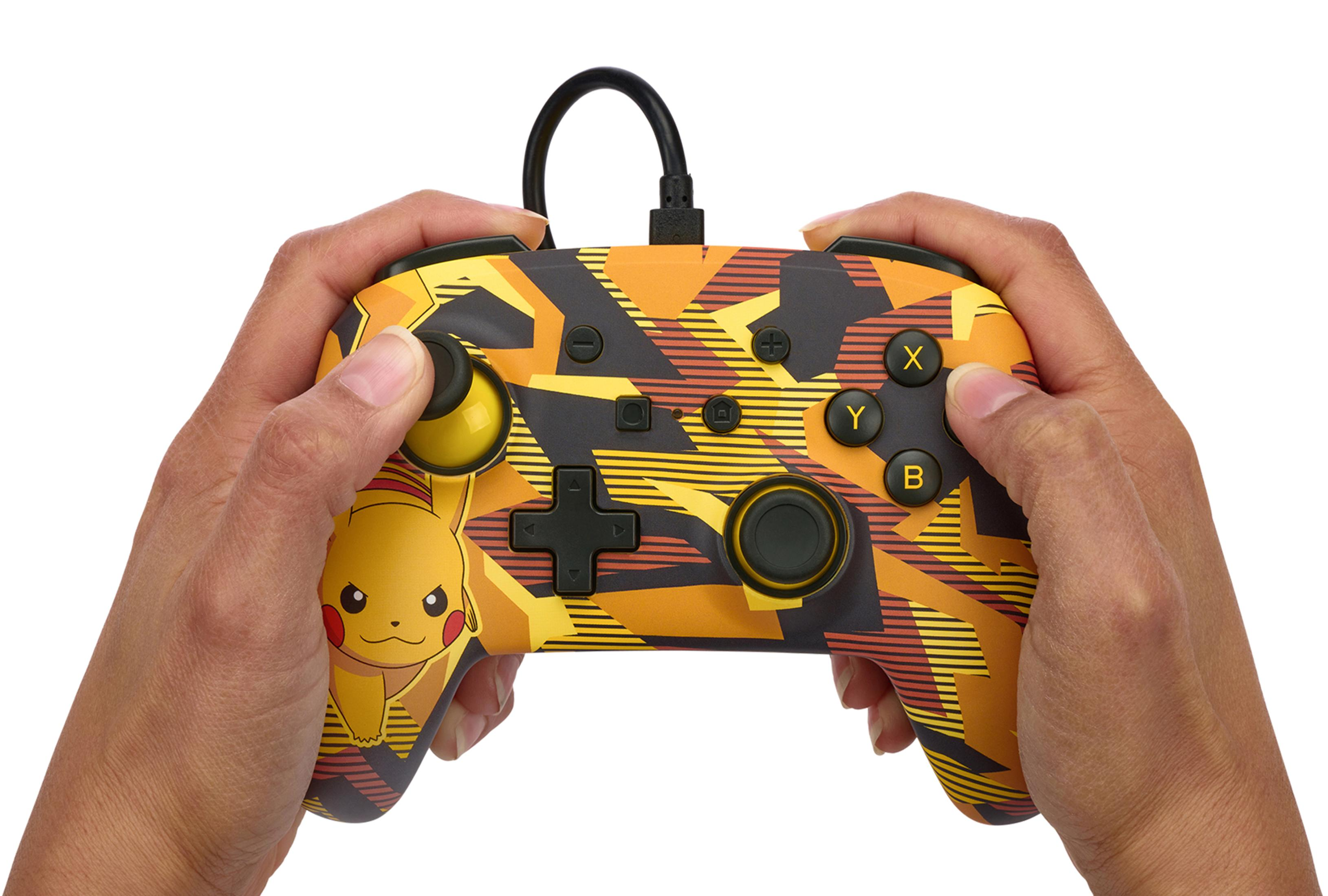 Dłonie trzymające pomarańczowo-żółty kontroler do gier w stylu Pikachu.