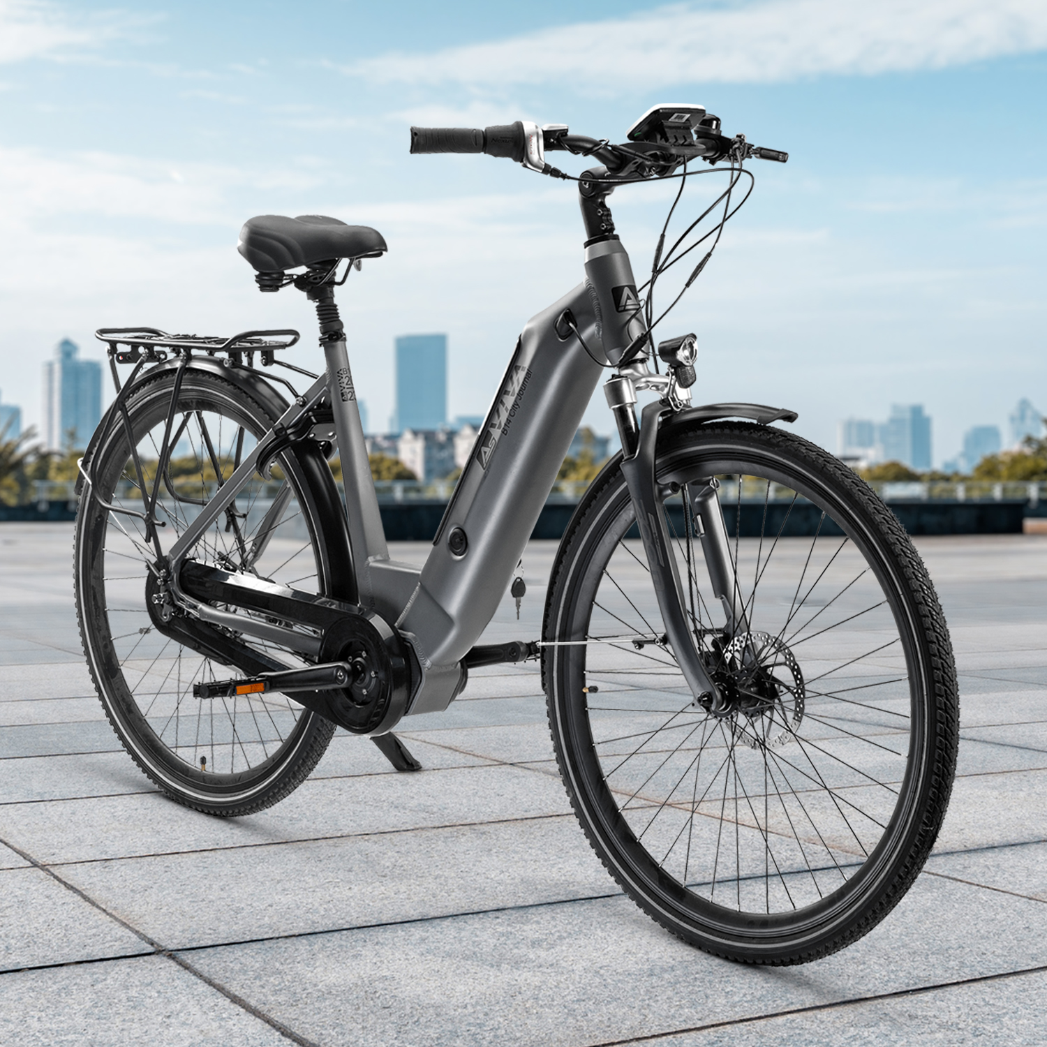 Graues Elektrofahrrad auf Pflaster mit Stadtkulisse und blauem Himmel. Fahrrad hat schwarze Reifen.
