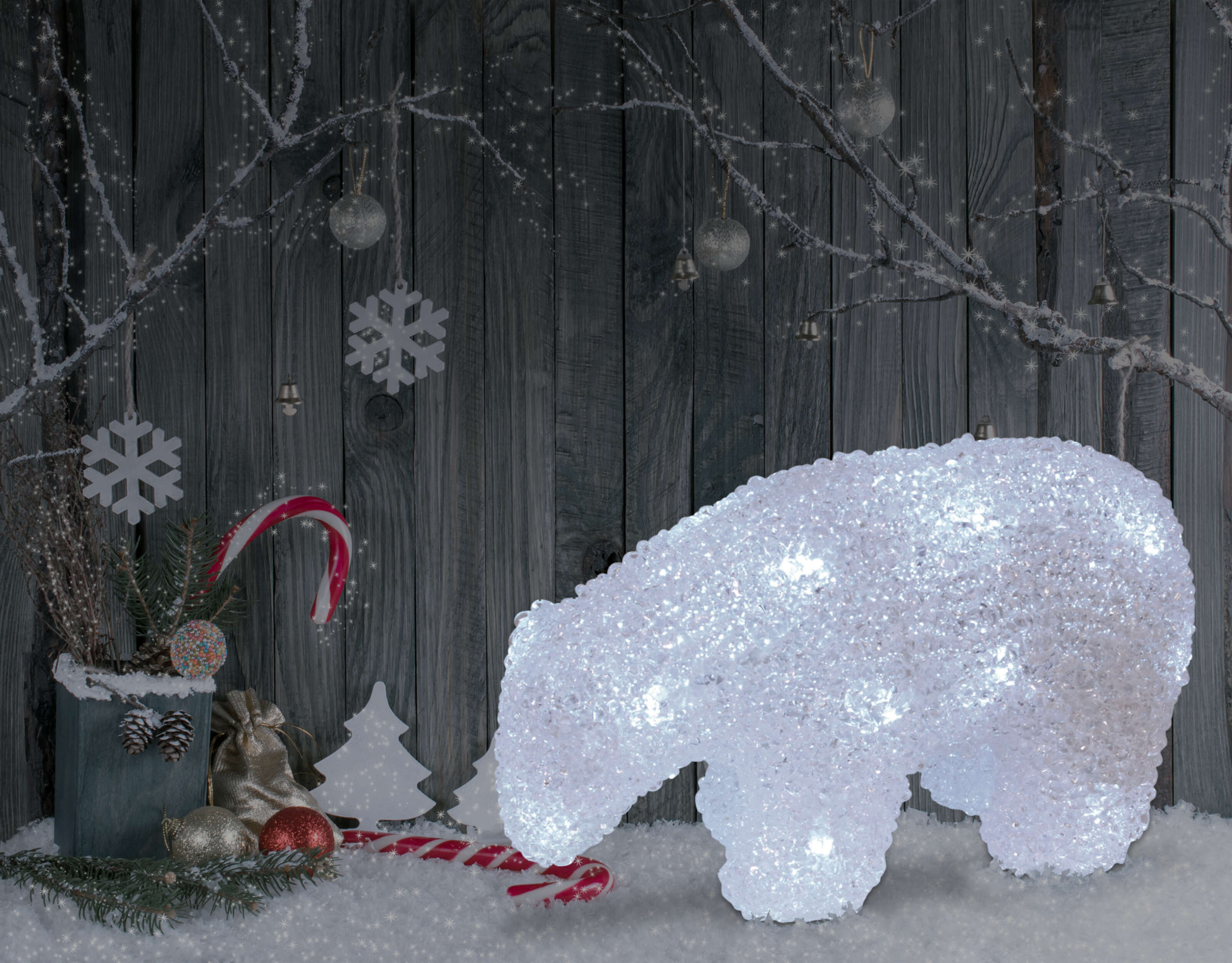 Beleuchteter Eisbär mit Weihnachtsdekorationen in einer schneebedeckten Szene.