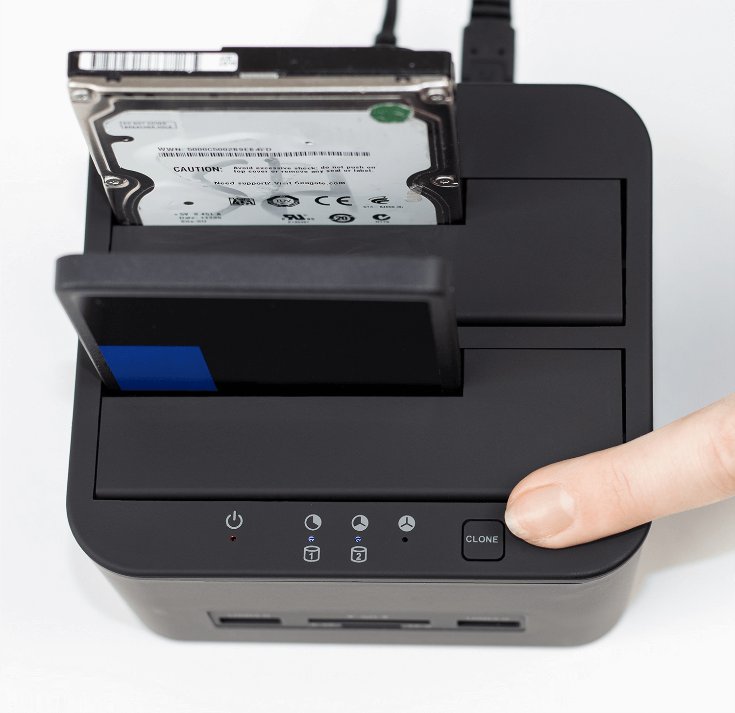 Czarne urządzenie z dyskami twardymi. Palec naciska przycisk Klonuj. Podłączony kabel USB.