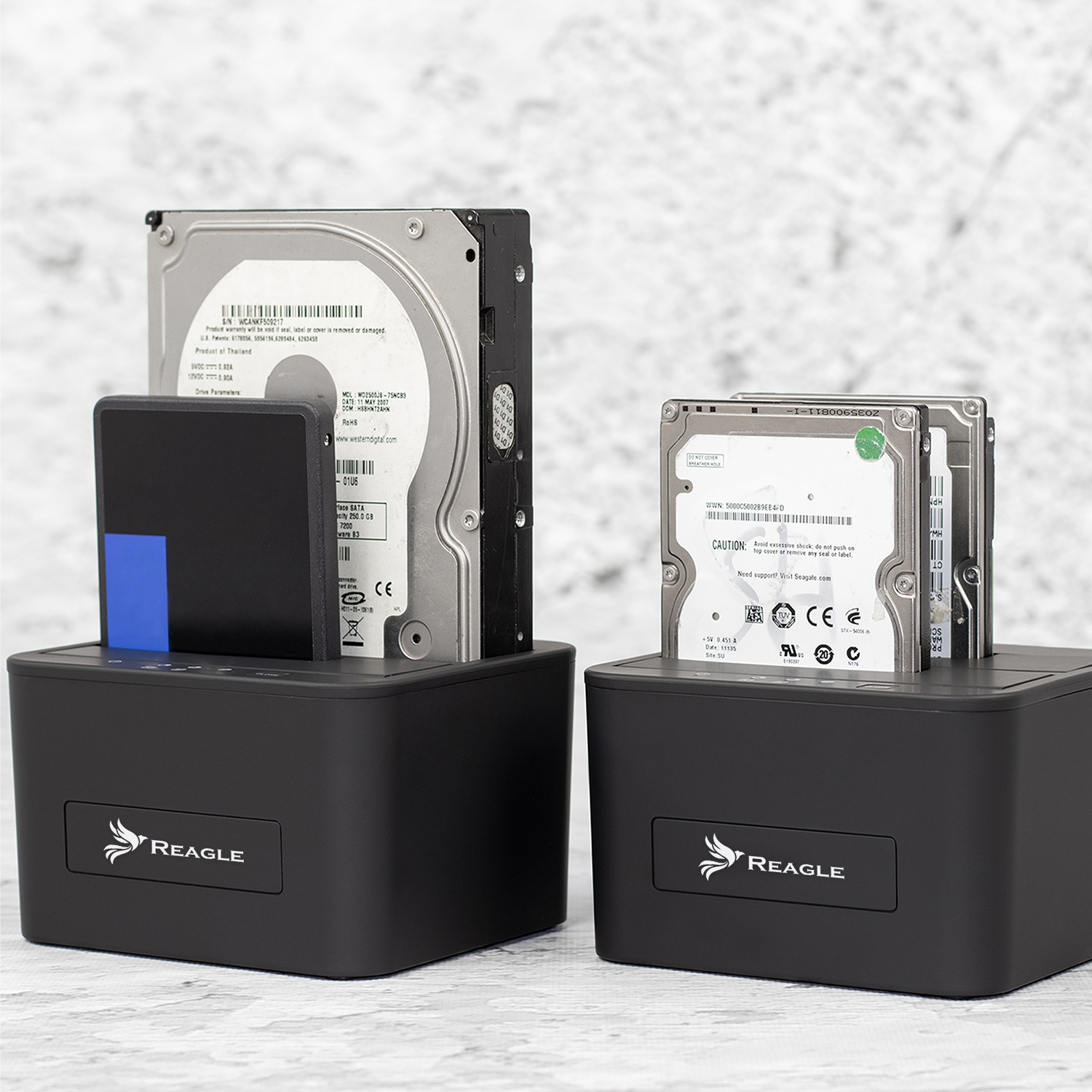 Dwie czarne stacje dokujące dysków twardych z dyskami twardymi i dyskiem SSD. Oznaczone są napisem 'REAGLE'.