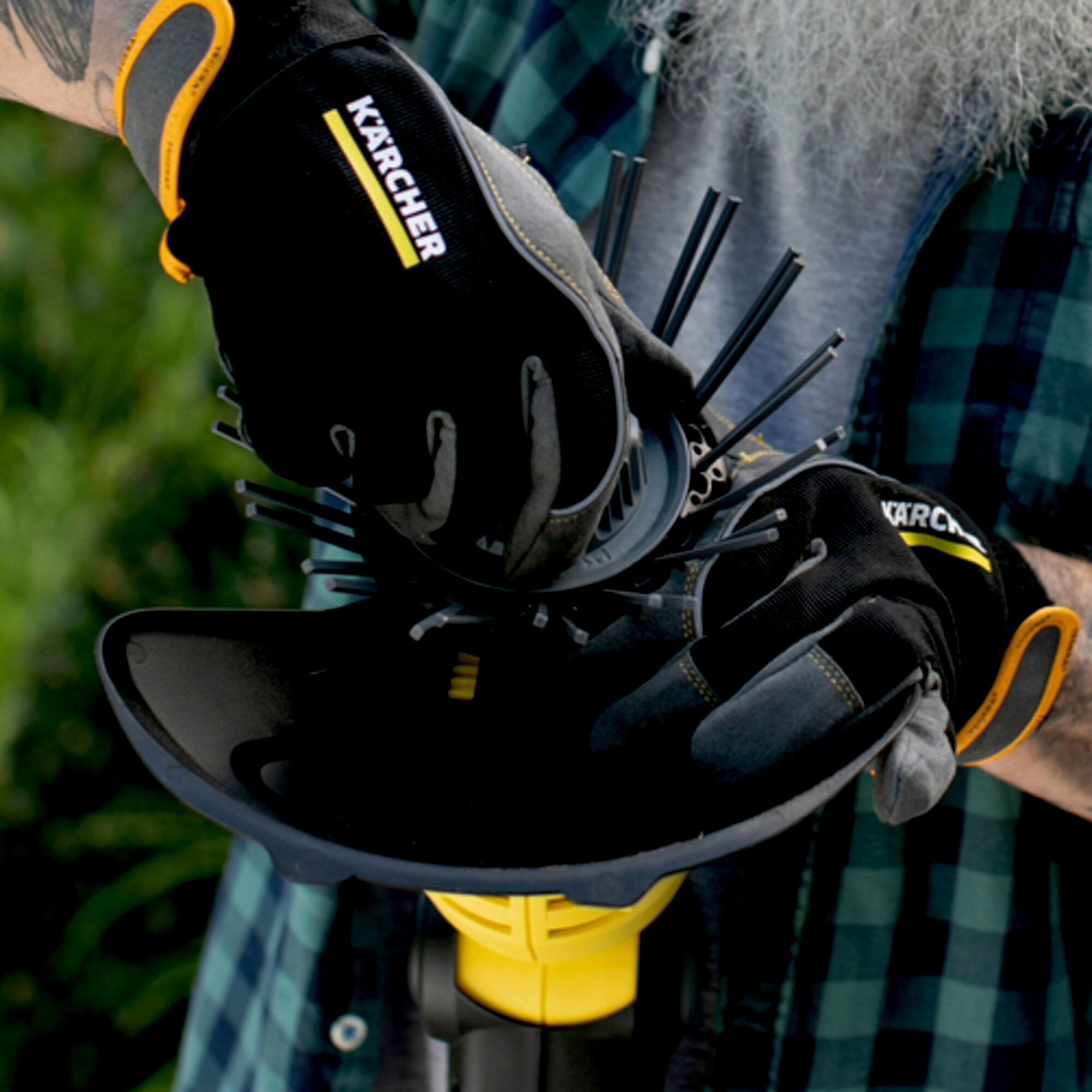 Osoba używająca rękawic Karcher i narzędzia do czyszczenia. Czarne rękawice i narzędzie.