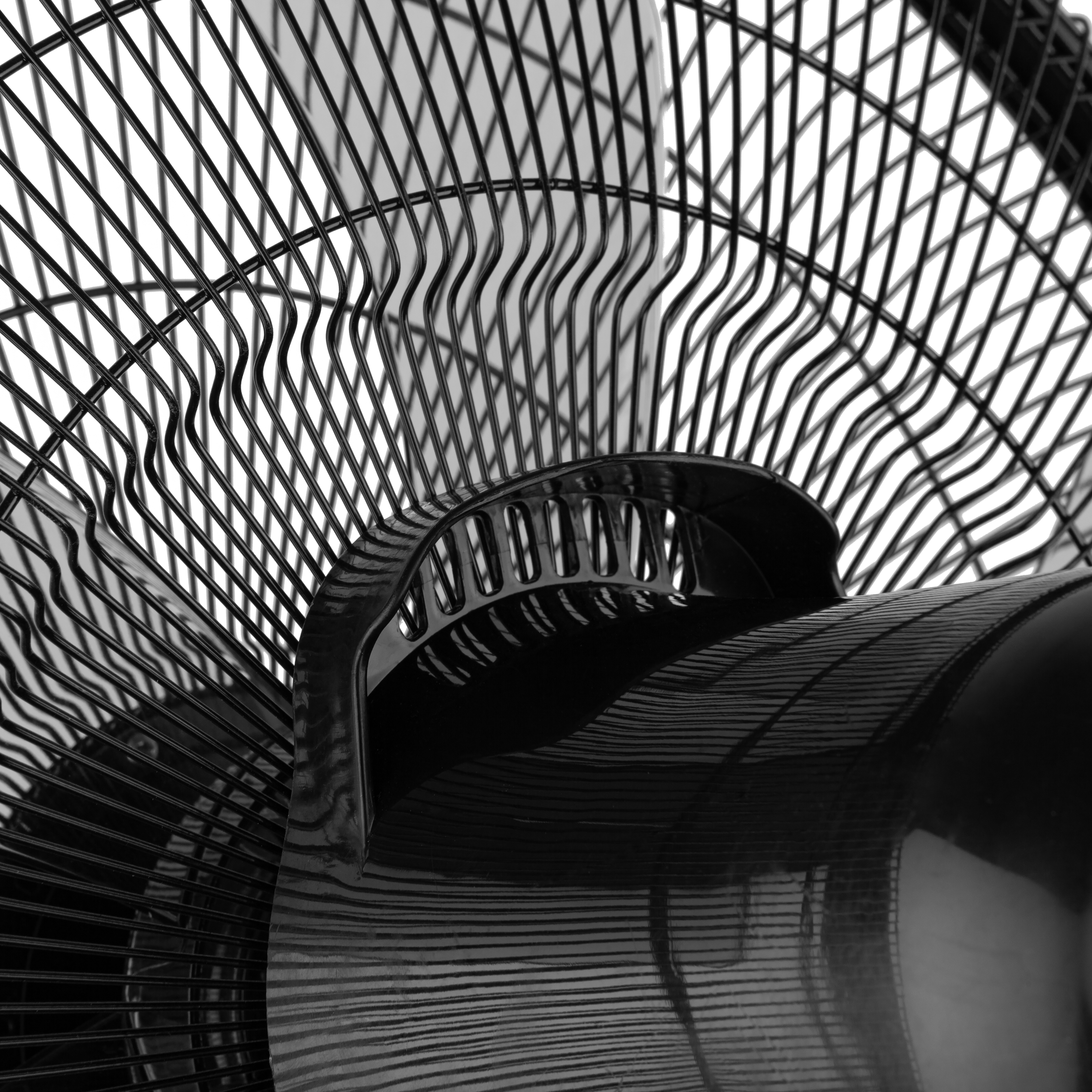 Czarny wentylator z zakrzywionymi łopatkami i kratką ochronną.