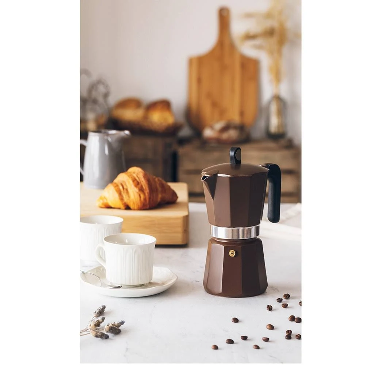 Kawiarka i filiżanka z rogalikiem. Umieszczone na białej powierzchni, z drewnianą deską i tłem.