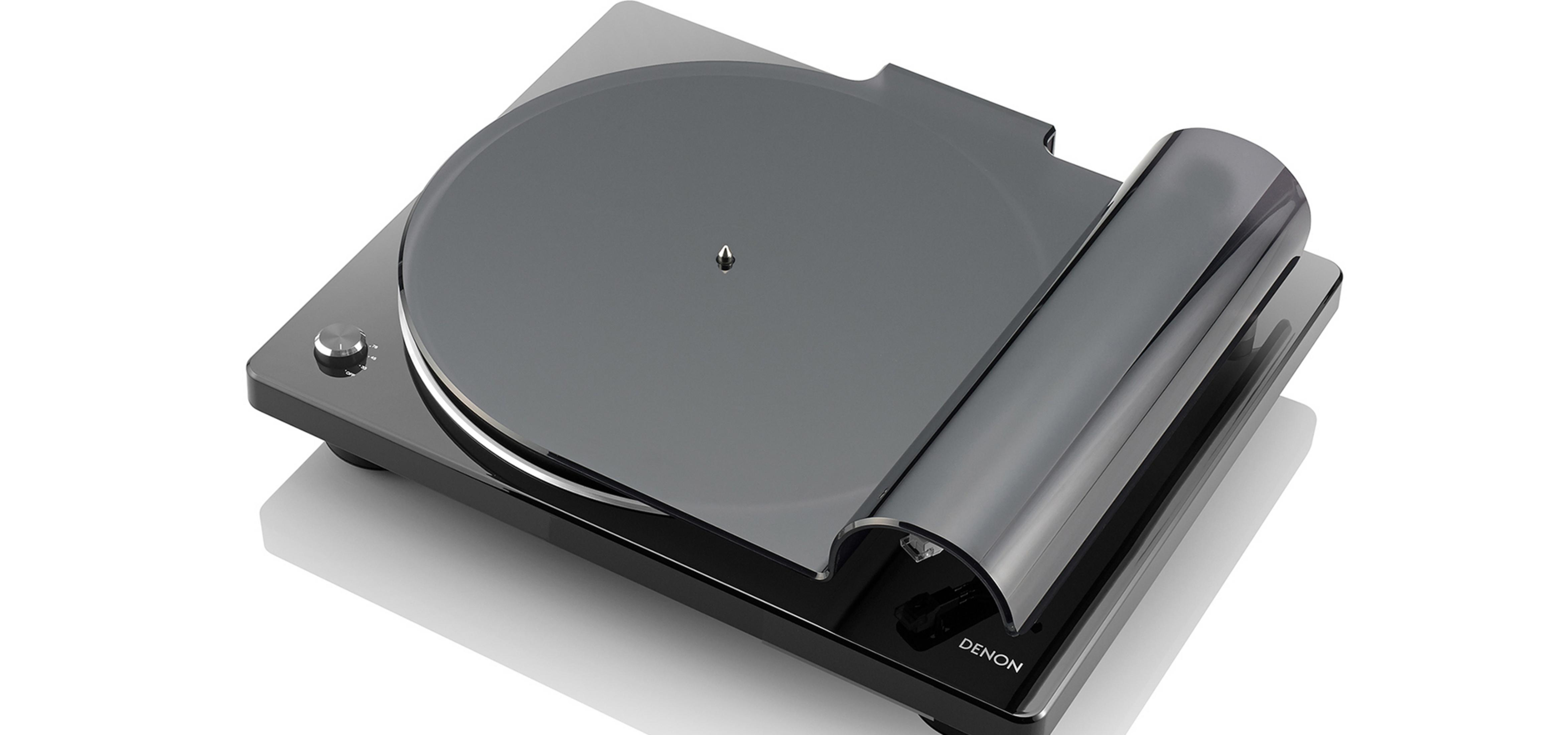 Un tocadiscos Denon negro con una cubierta transparente. Está sobre un fondo blanco y tiene un diseño elegante.